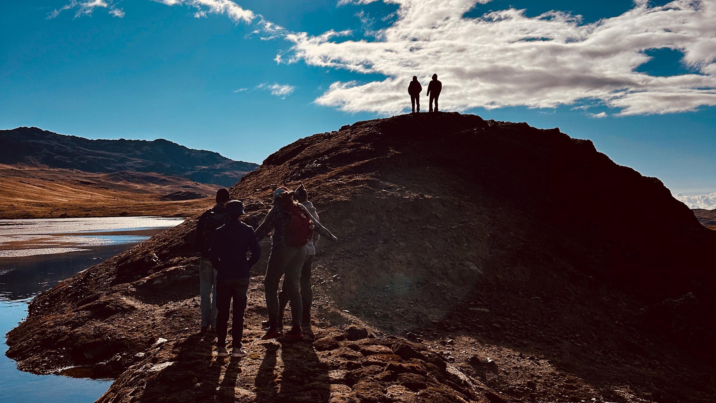 Students stand atop a hill against a dramatic sky.