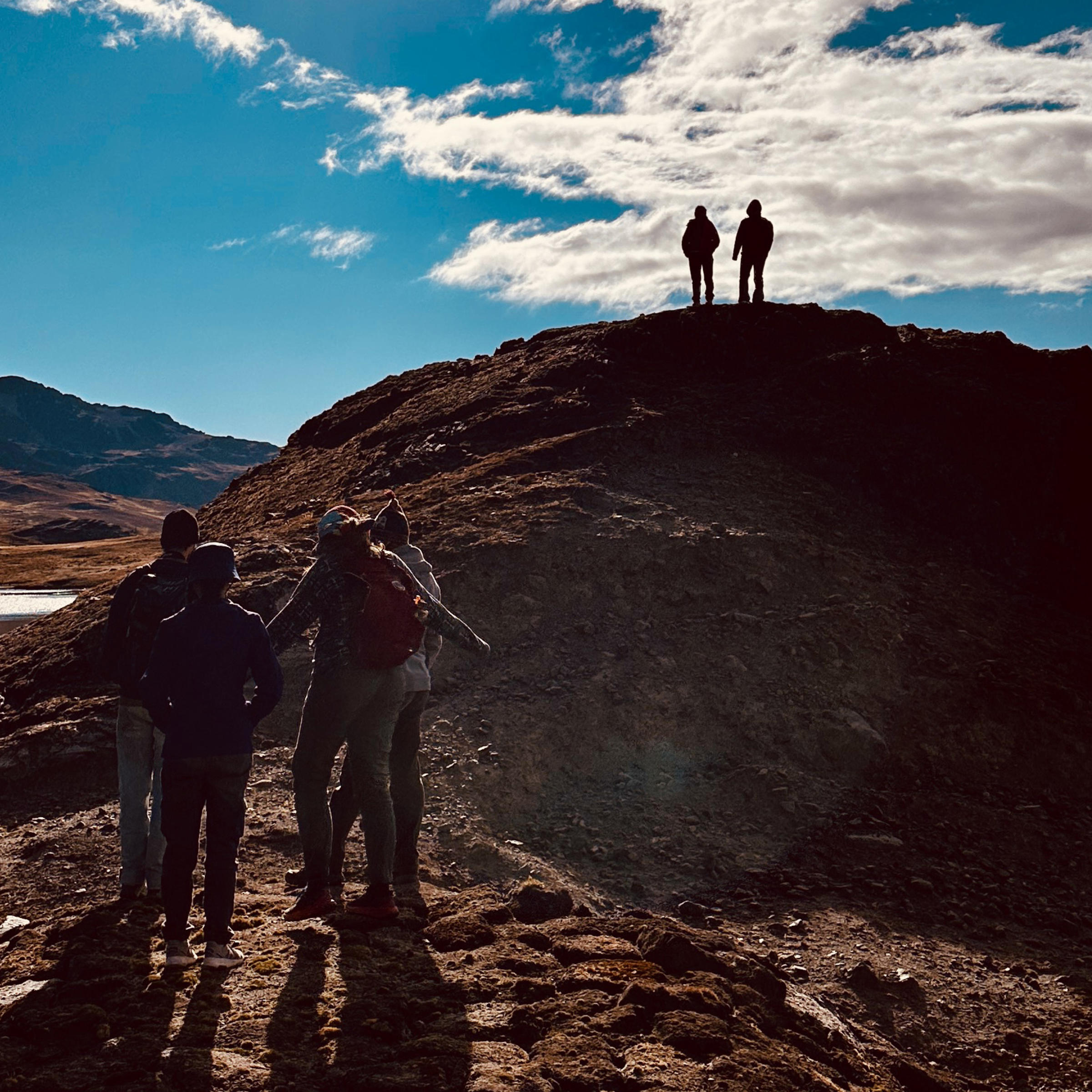 Students stand atop a hill against a dramatic sky.