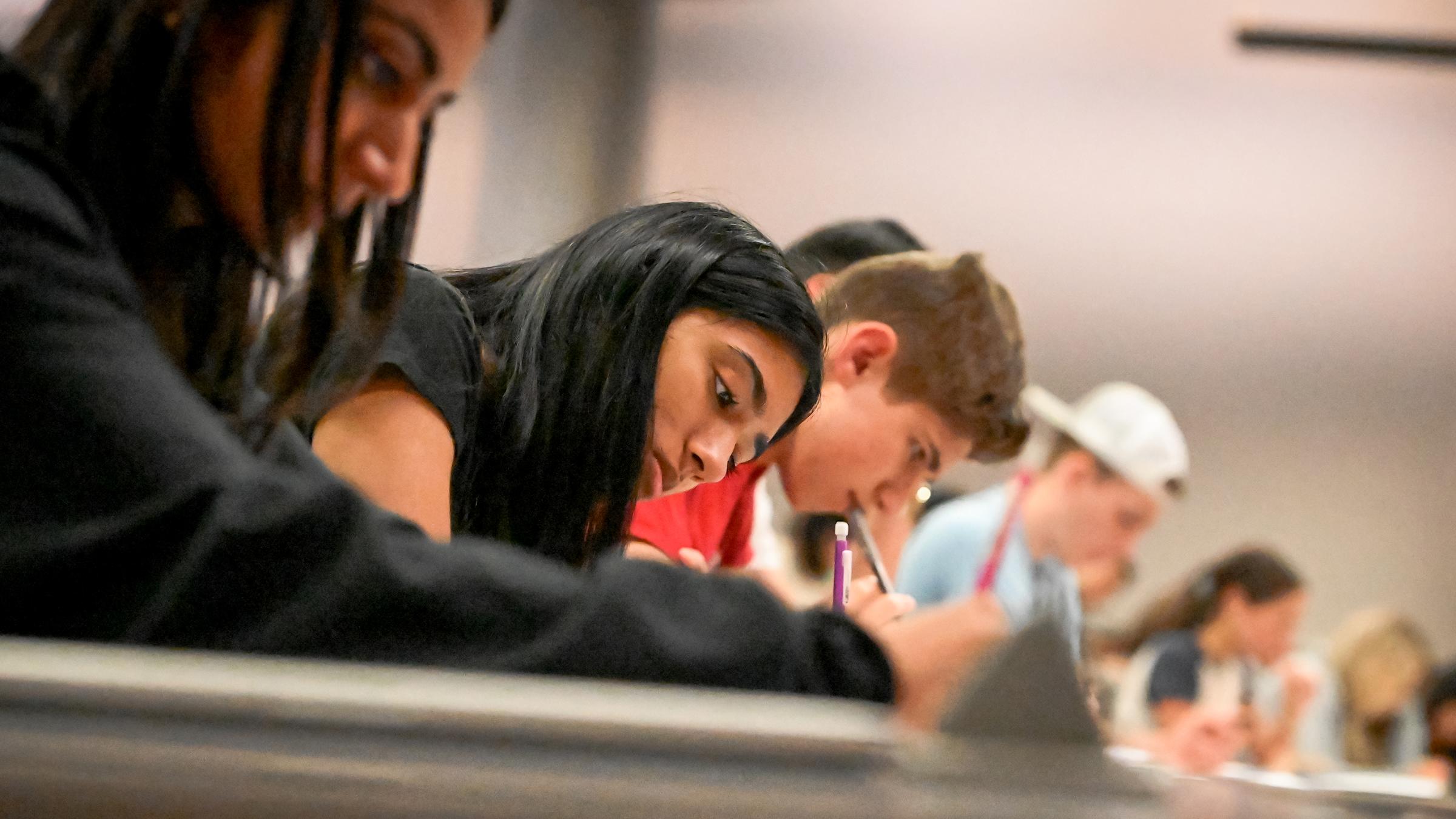 Students in class bent over their desks writing.