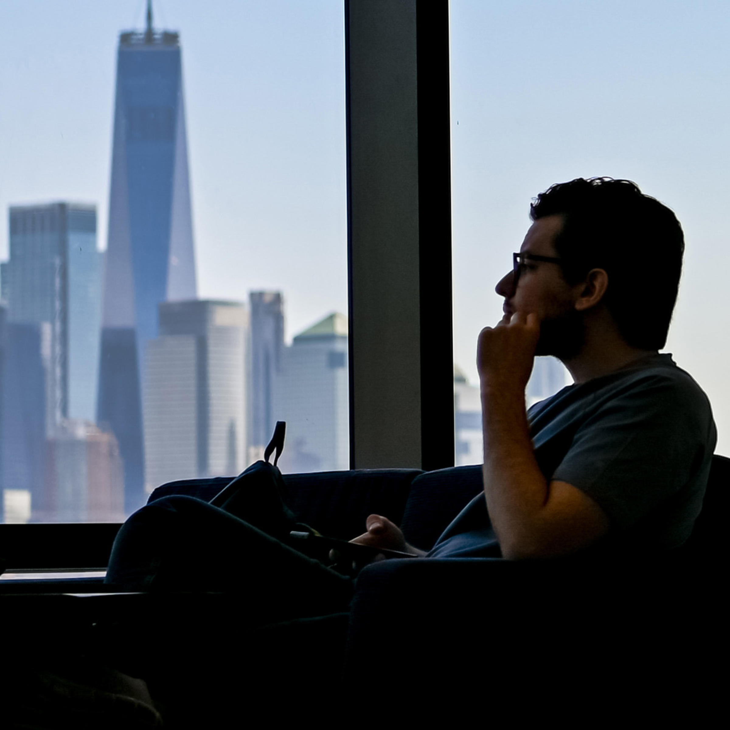 Student inside UCC looks out window at New York skyline.