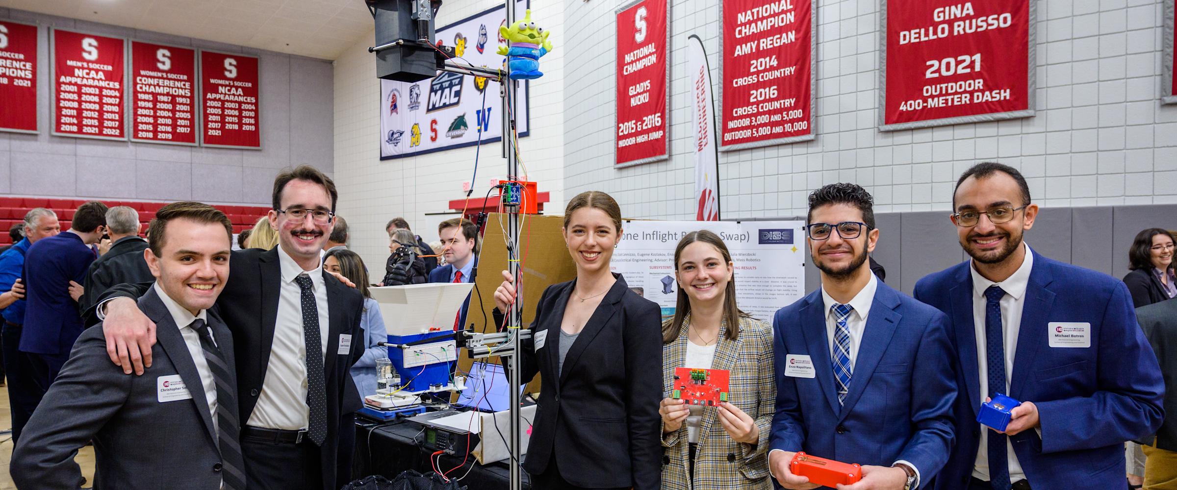 Students pose alongside their senior capstone project during Innovation Expo 2023 at Stevens.