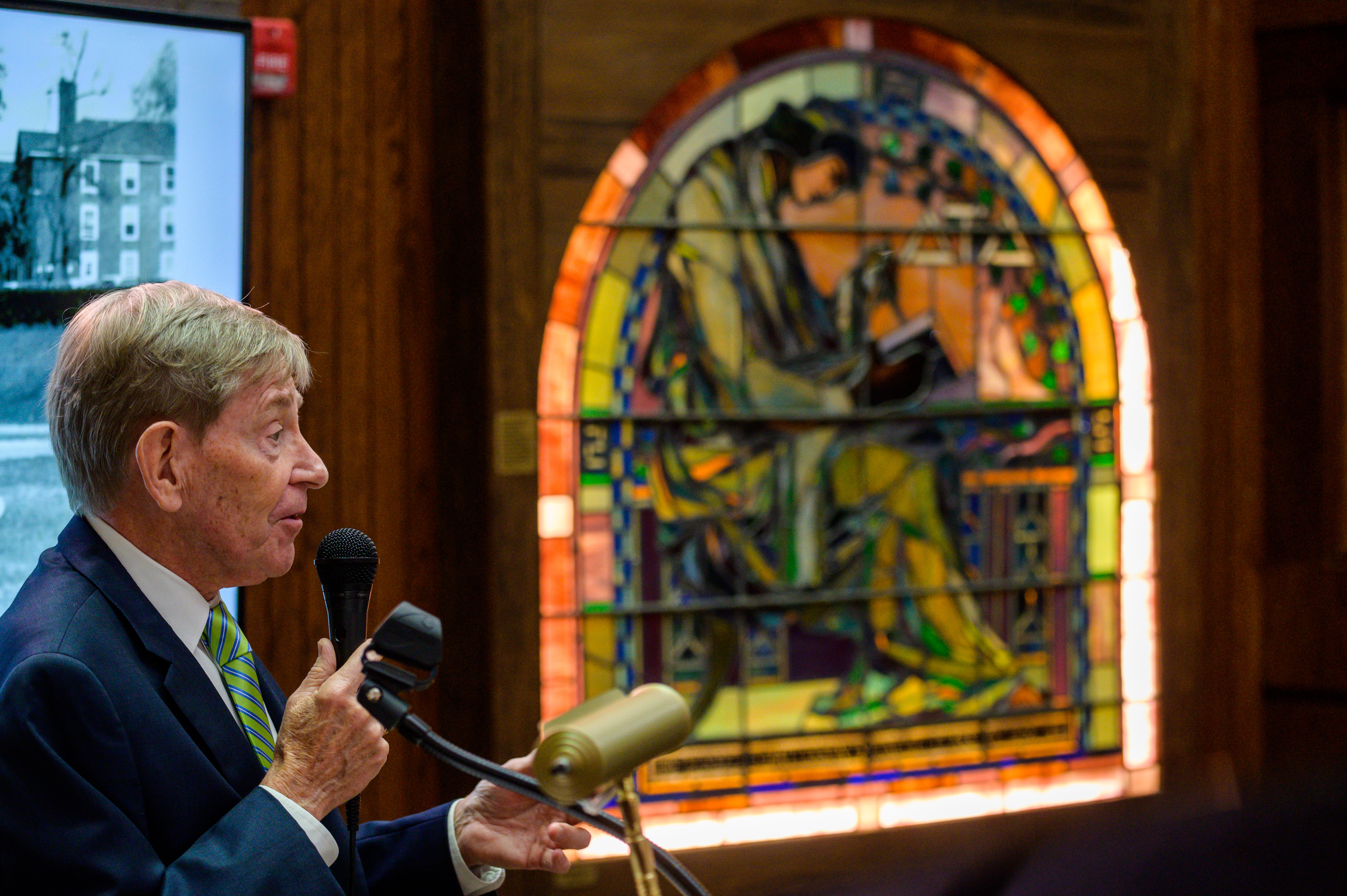 John Dalton stands at the Delta Tau Delta Wall of Achievement in the library