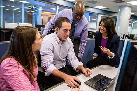 Four people working at a laptop