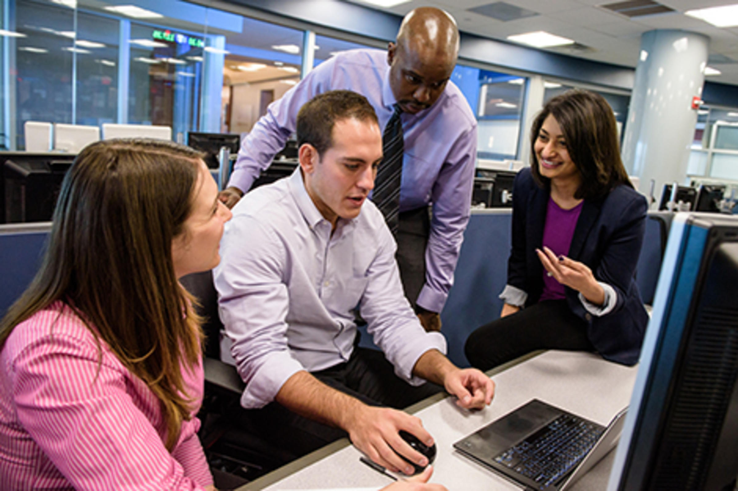 Four people working at a laptop