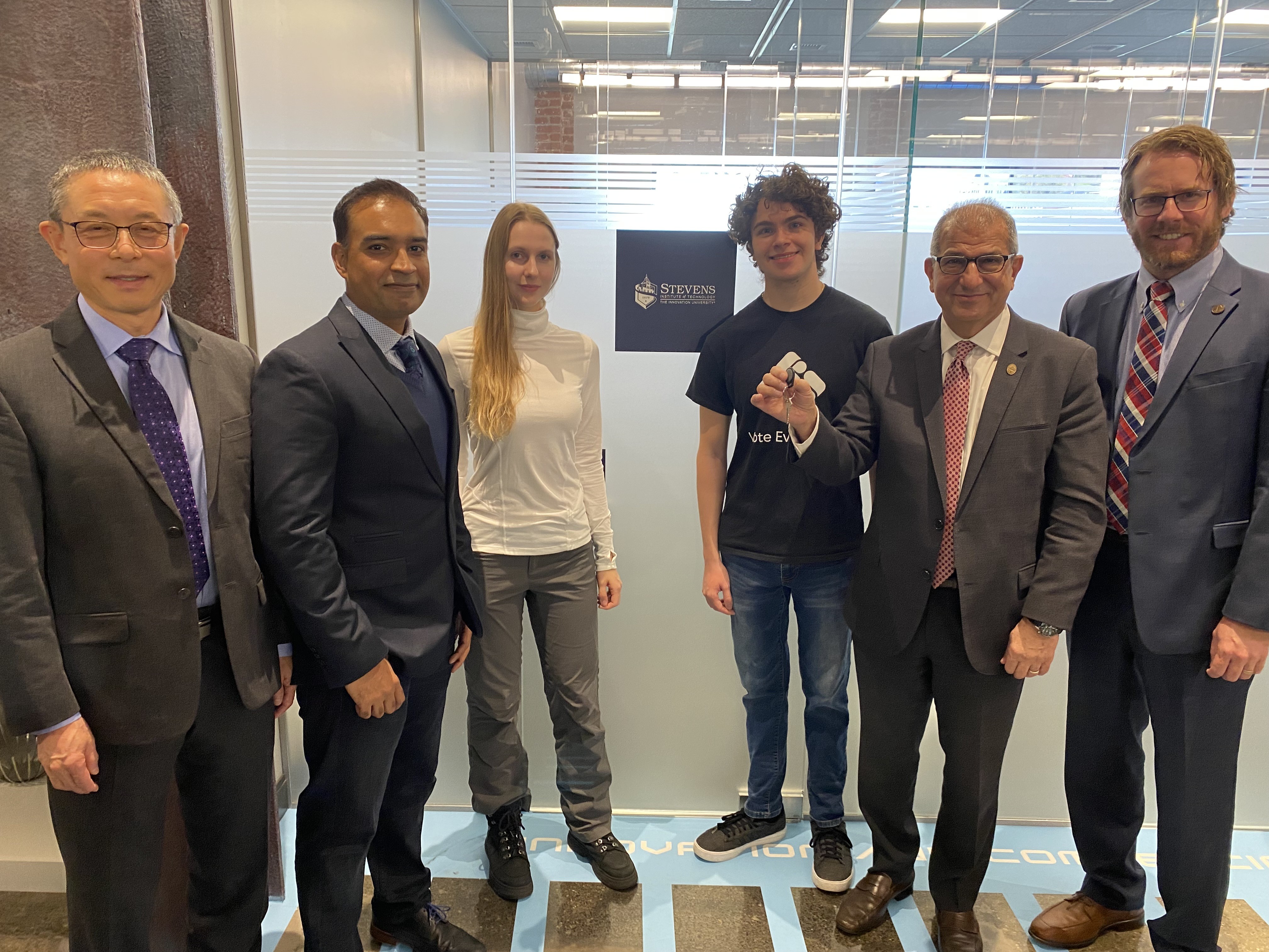 Six people smiling in front of Stevens research pod at Mission 50