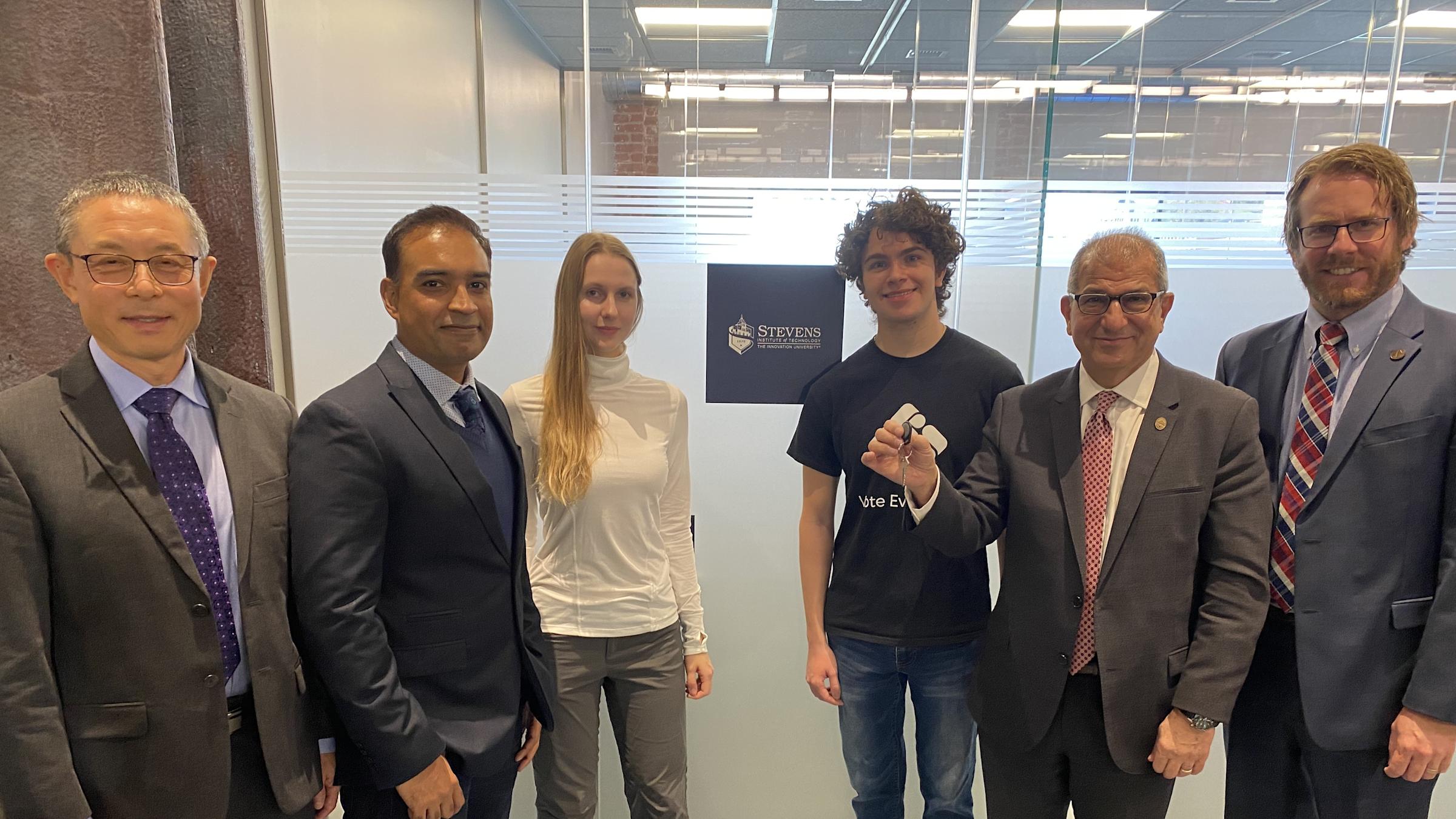 Six people smiling in front of Stevens research pod at Mission 50