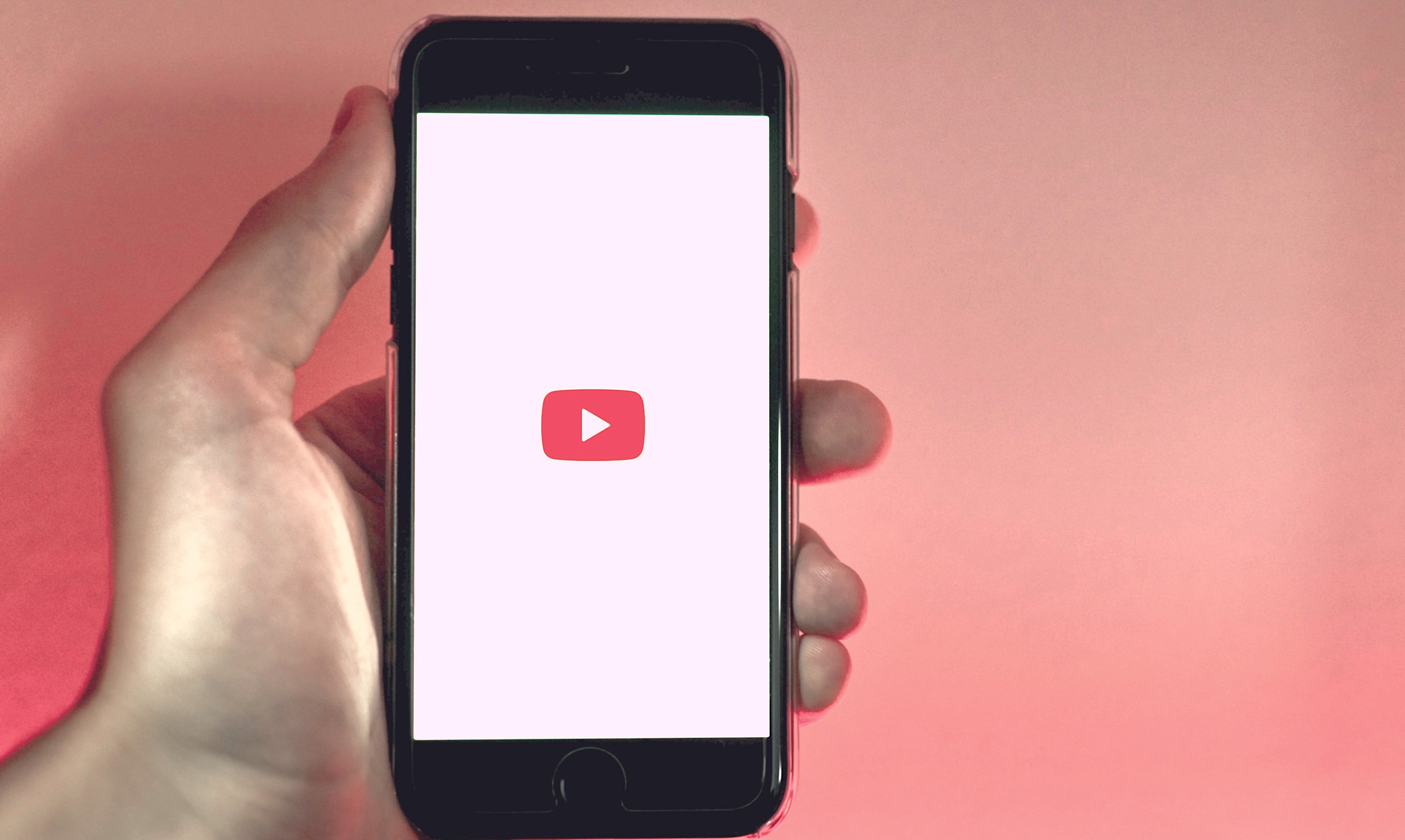 Hand holding phone with Youtube logo on screen