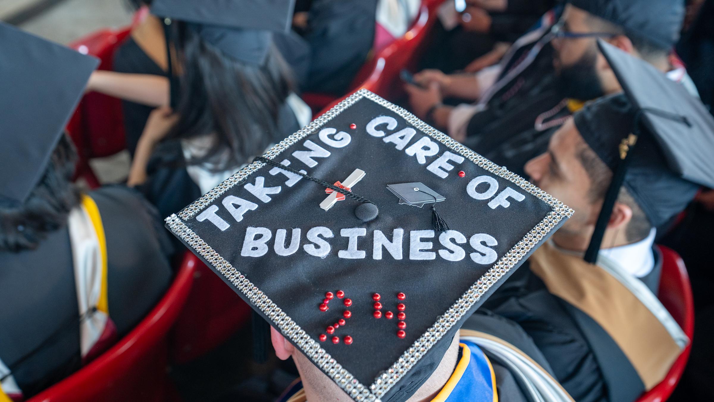 Back of the headshot of a graduation cap that says "Taking care of business 2024"