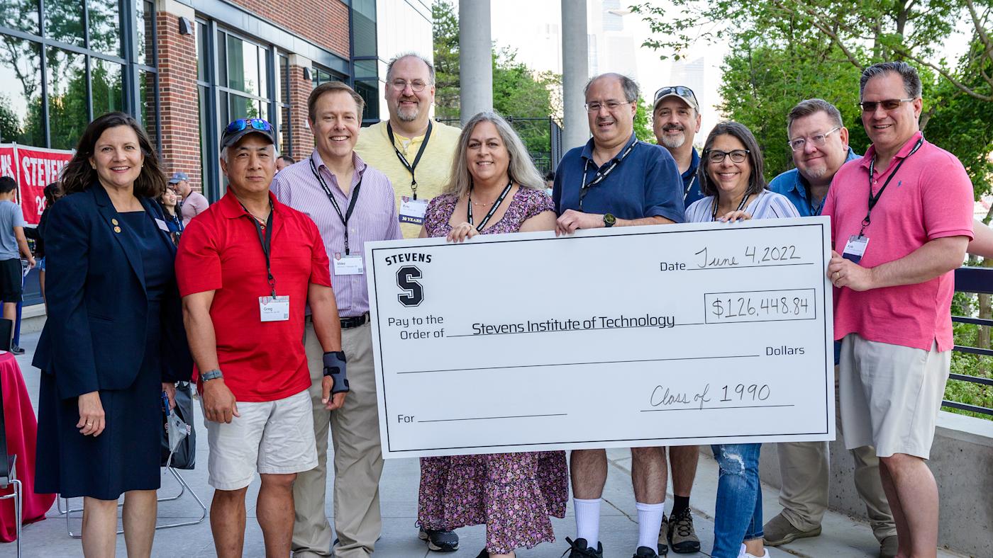 Group of Stevens alumni pose with giant donation check.