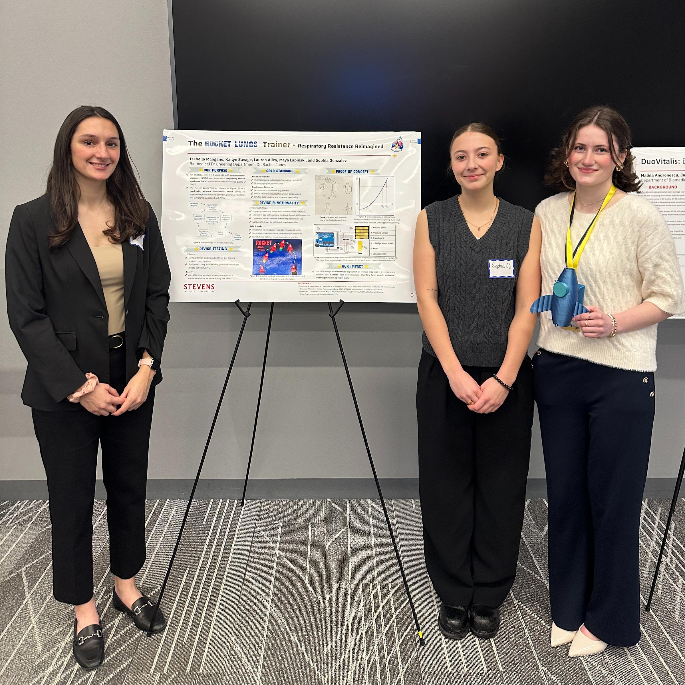 Three female students pose for a photo with their presentation poster during the fourth annual Biomedical Engineering Day.
