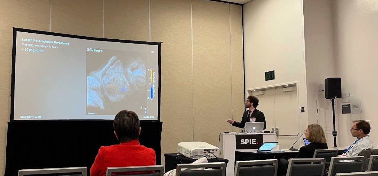 Faubert stands behind a podium, in front of an audience, presenting his research projected onto a large screen