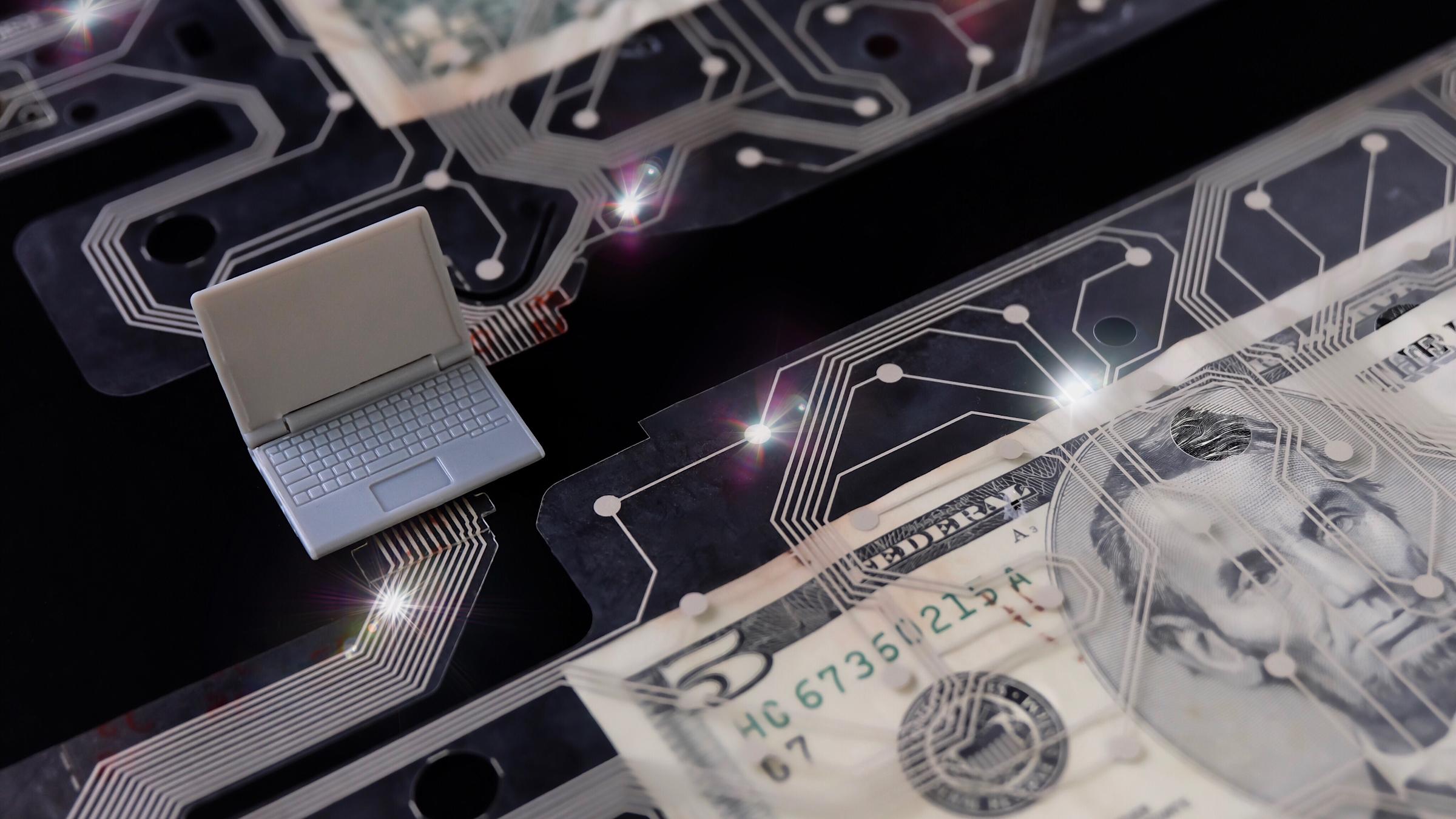 Representation of digital money with a plastic laptop, $5 bill and circuit board.