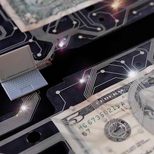 Representation of digital money with a plastic laptop, $5 bill and circuit board.