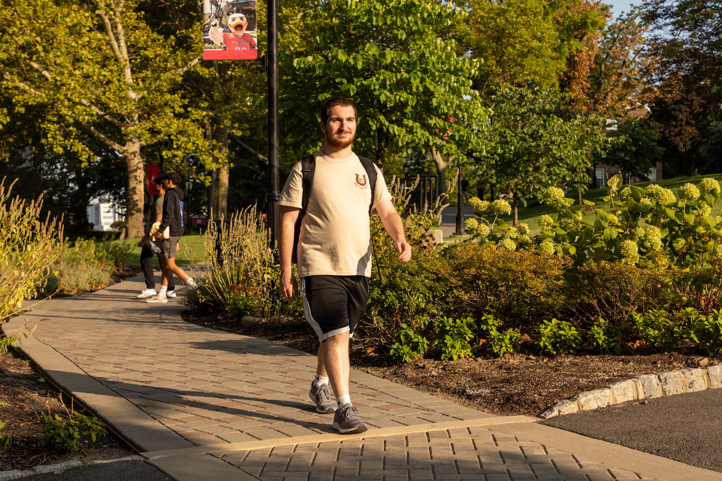 Chris Alessandri walks on campus under a golden sun.