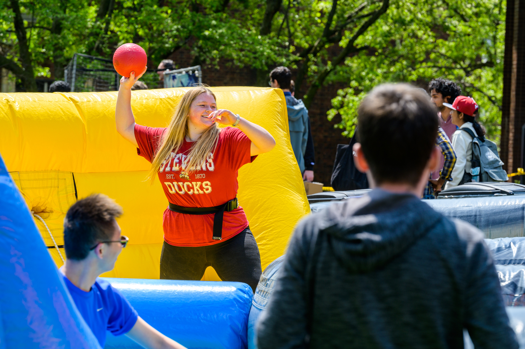 A woman throws a nerf ball while bouncing on an inflatable structure at Spirit Day 2023.