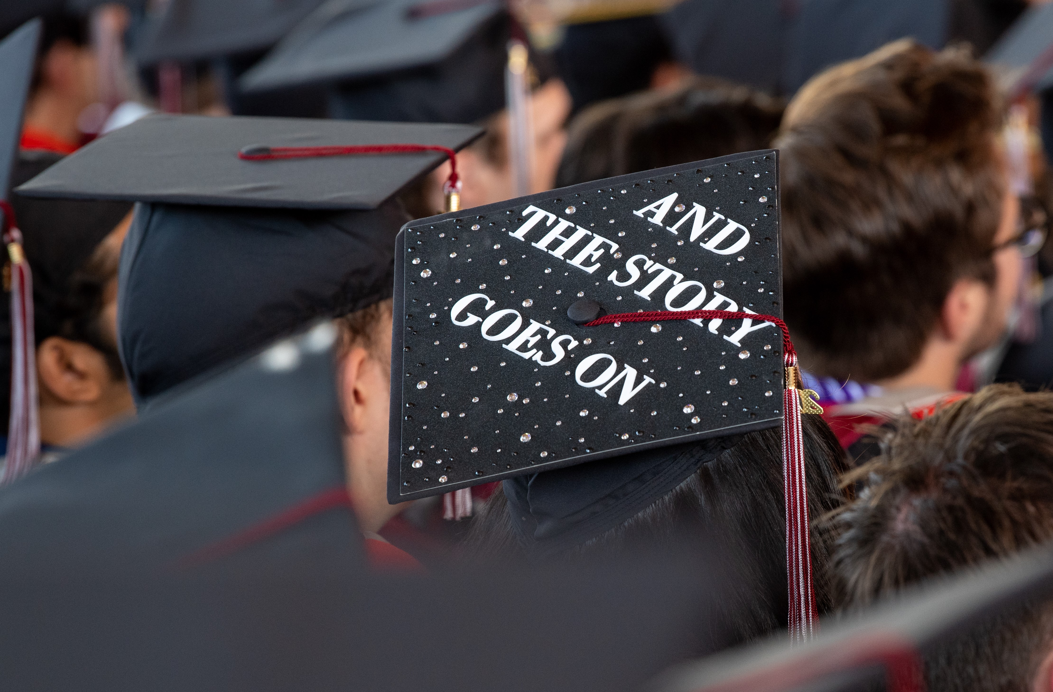 A graduation cap that is decorated with beads and the words "And the story goes on."