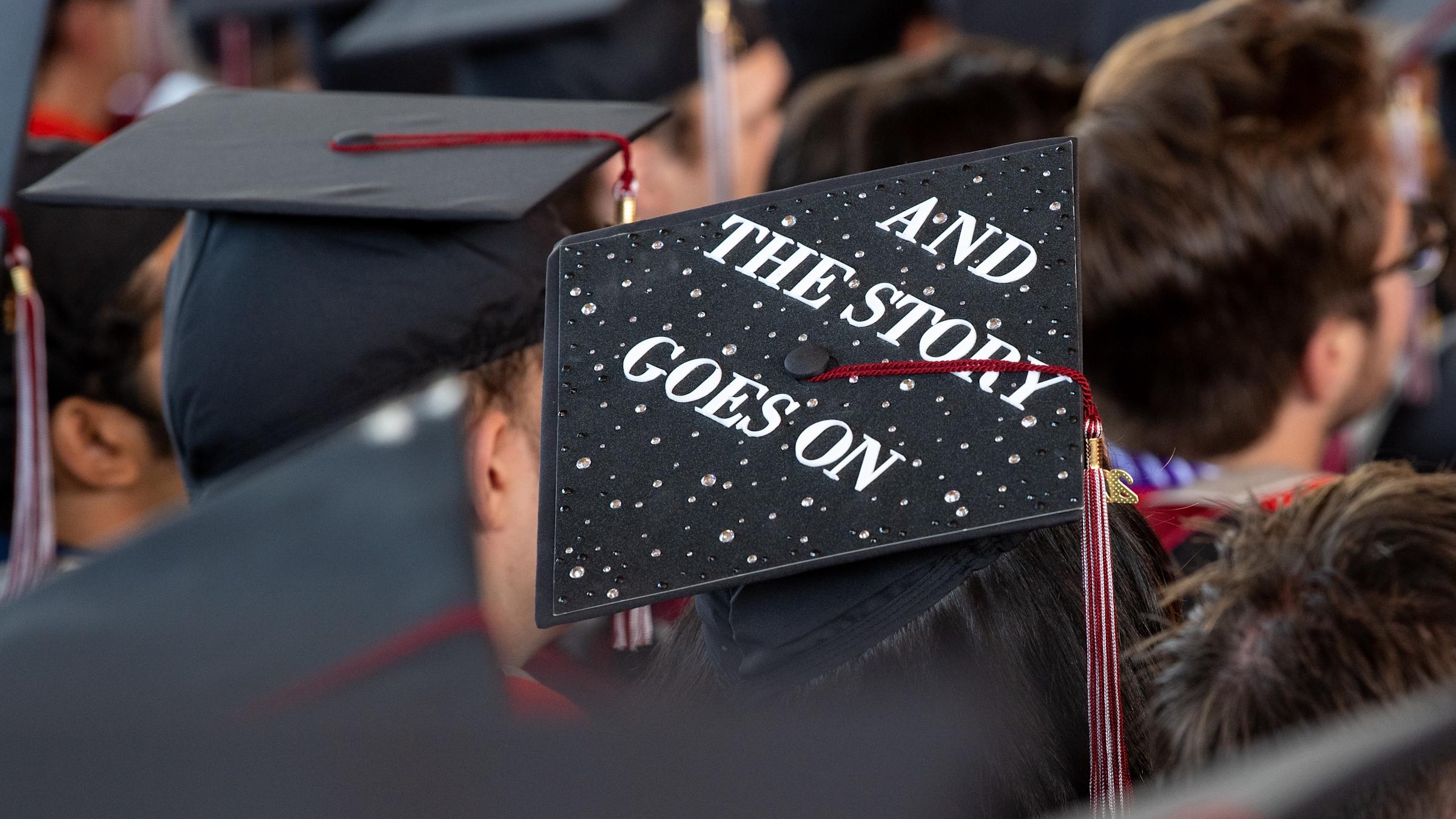 A graduation cap that is decorated with beads and the words "And the story goes on."