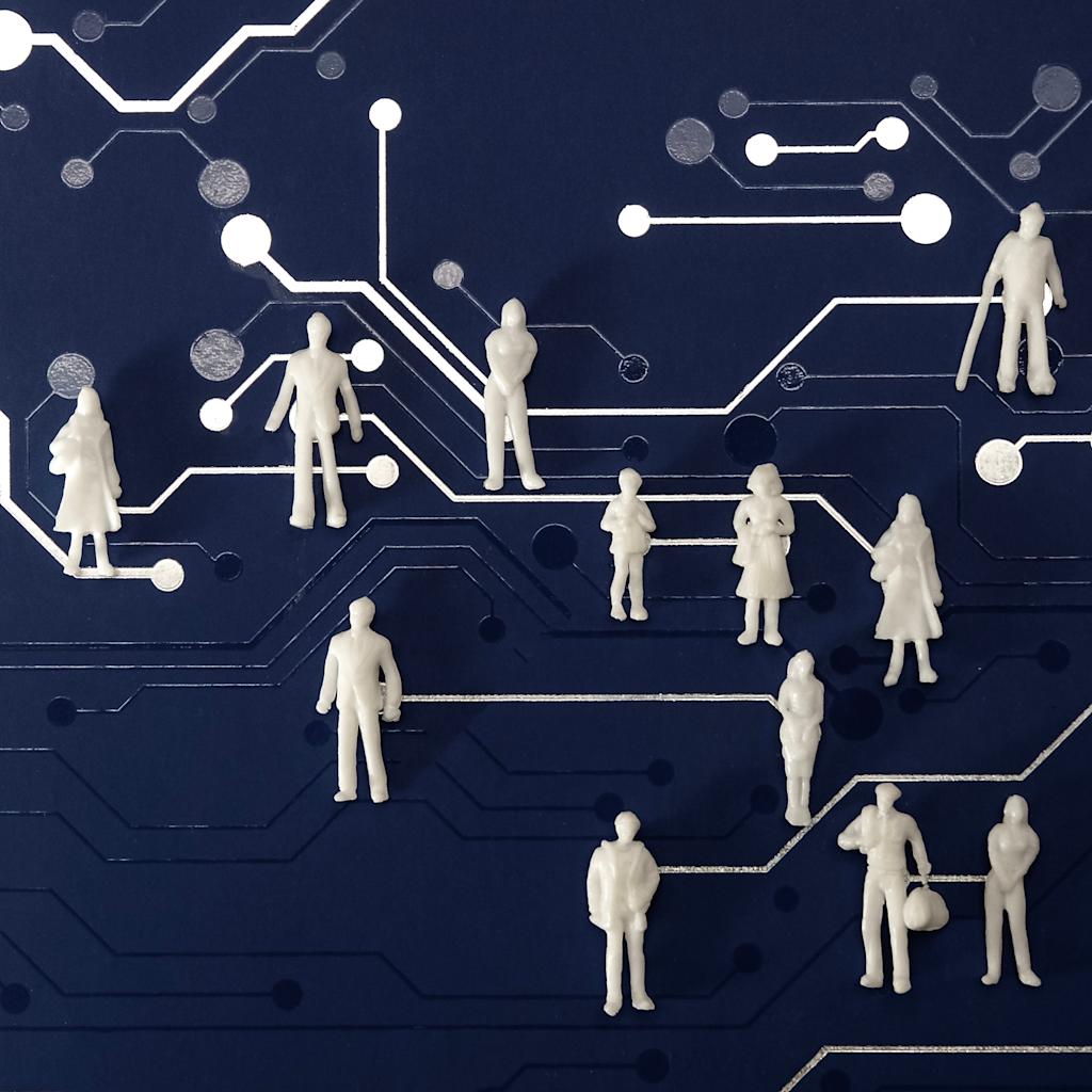 A collection of small, white, unidentifiable figures stand atop a blue surface patterned with white lines and circles that resemble a circuit board.