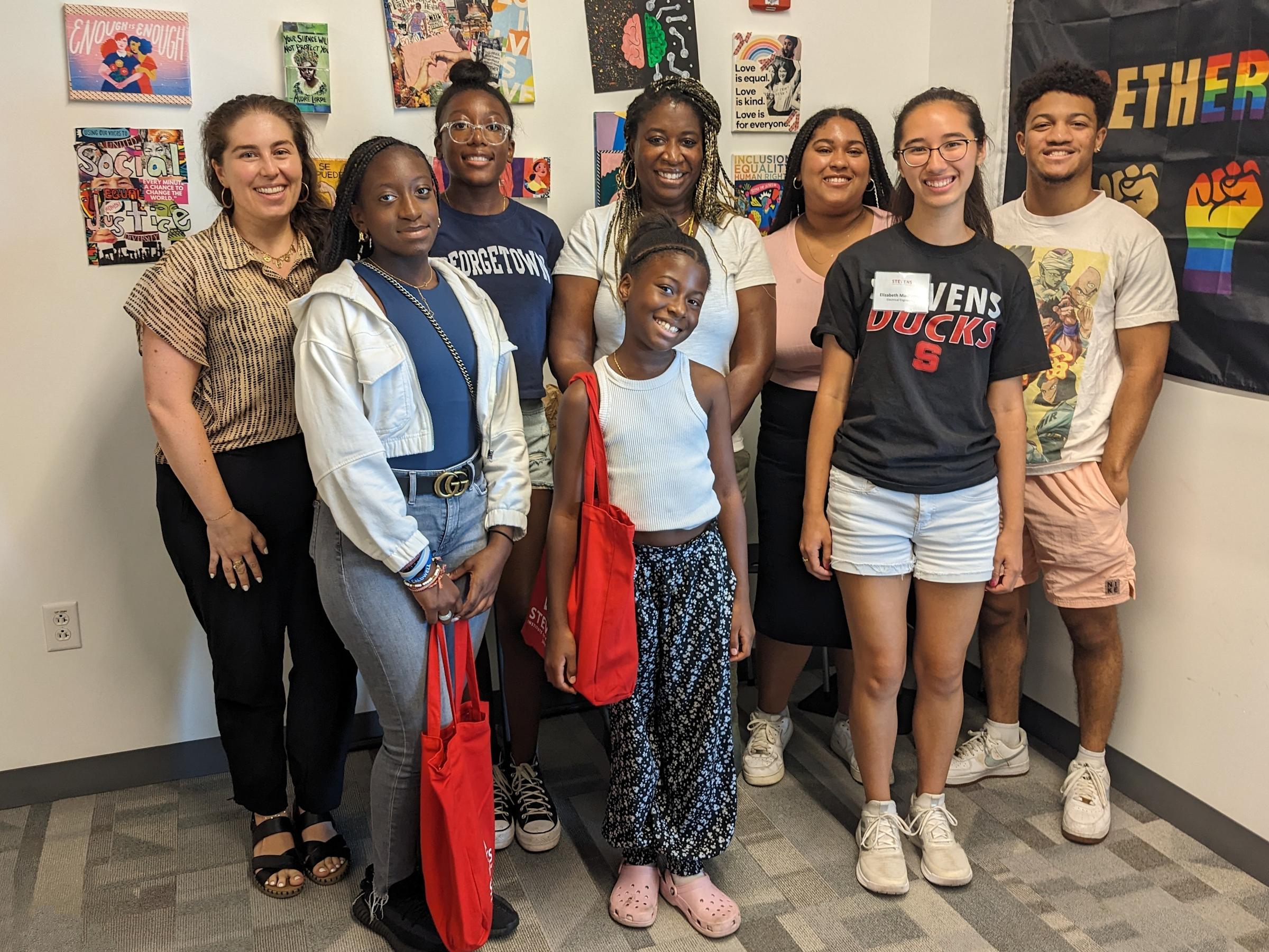 Group of people standing together in a room with art on the walls.