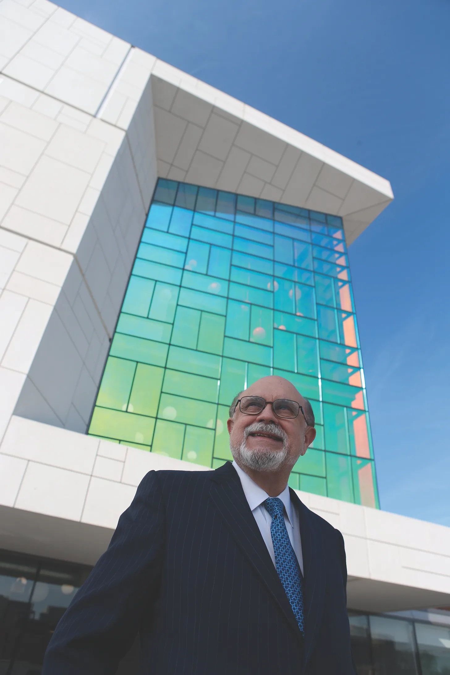 Emilio Fernandez stands in front of a glass building.