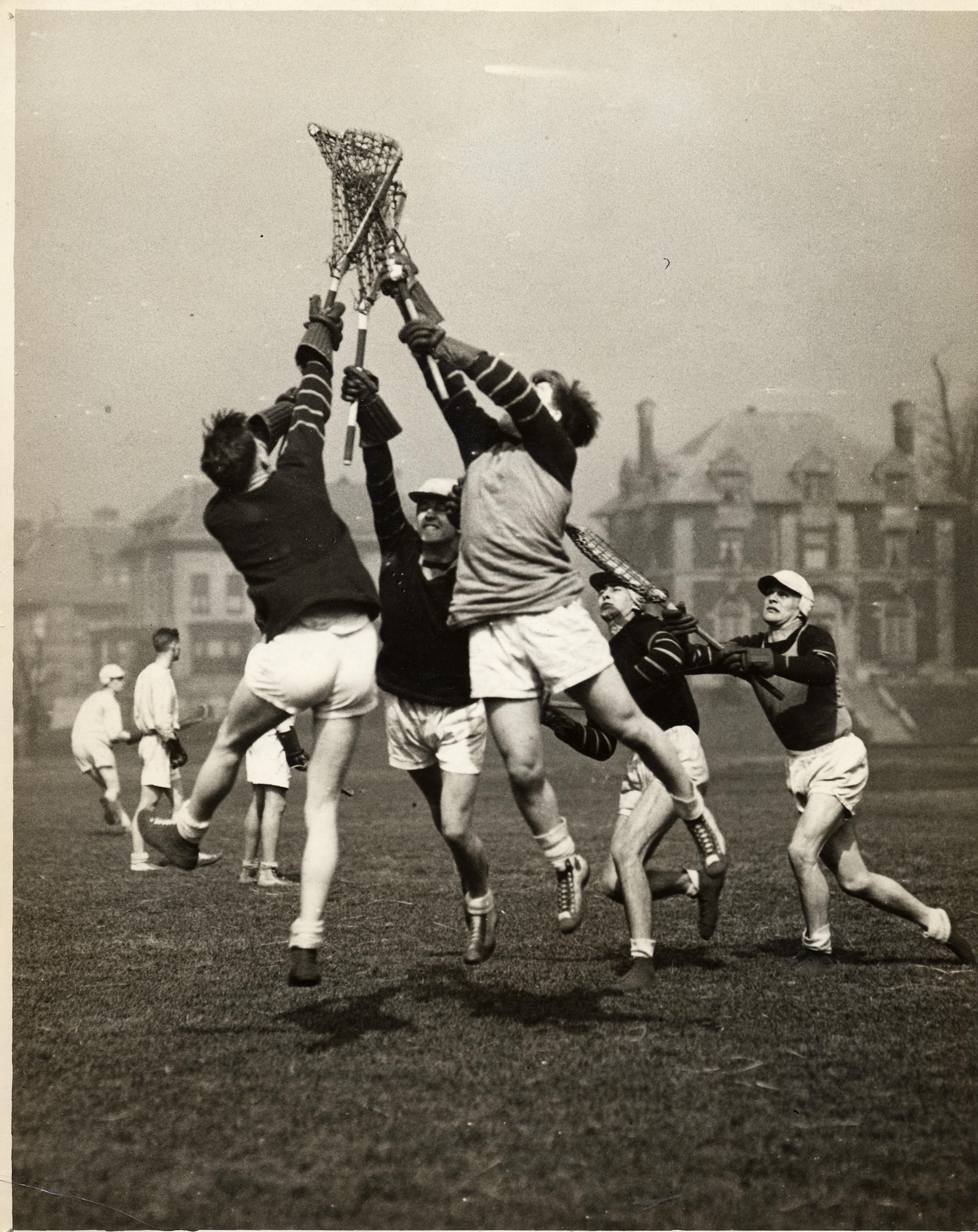 Black and white photo of Stevens Men's Lacrosse team reaching for a ball, circa 1930s