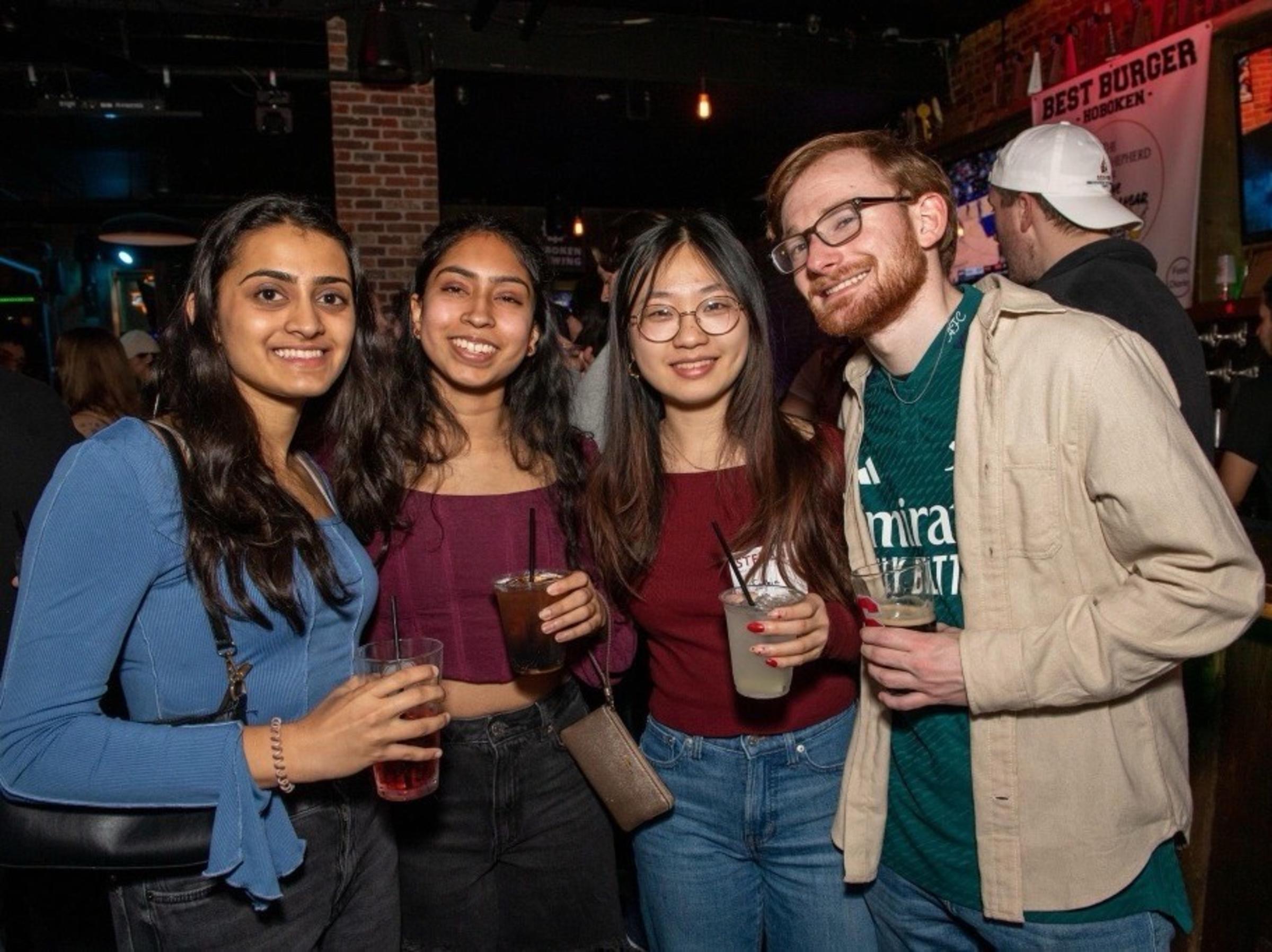 Four students pose at event in bar together