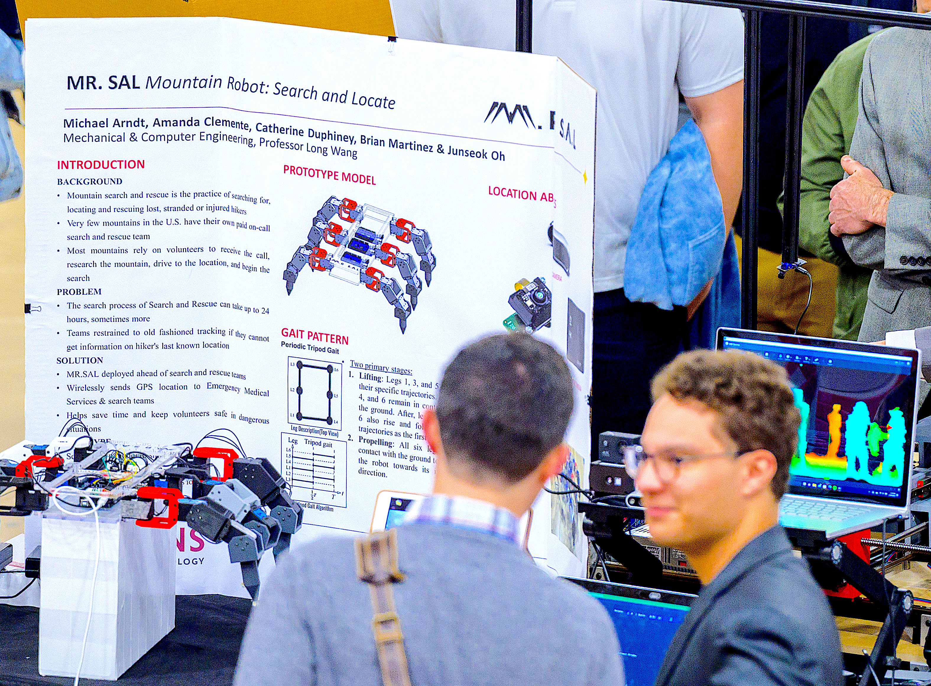 Student explains a crab-like robot to a visitor at the 2023 Stevens Innovation Expo