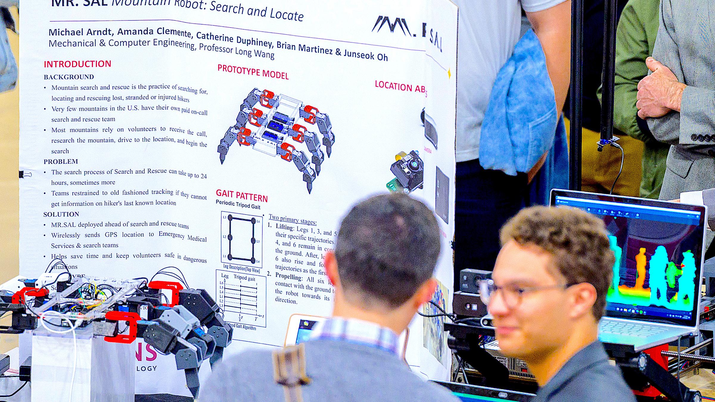 Student explains a crab-like robot to a visitor at the 2023 Stevens Innovation Expo