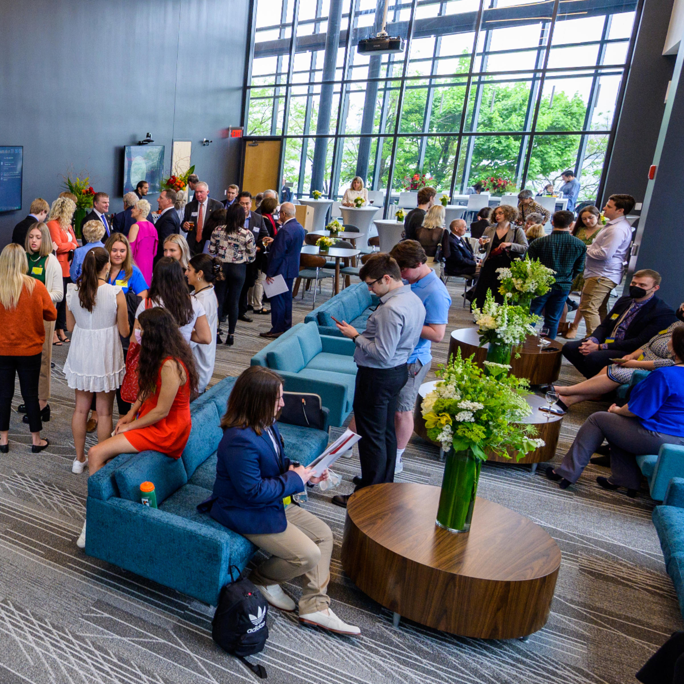 Group of people inside the gallery space, socializing or looking at their phones.