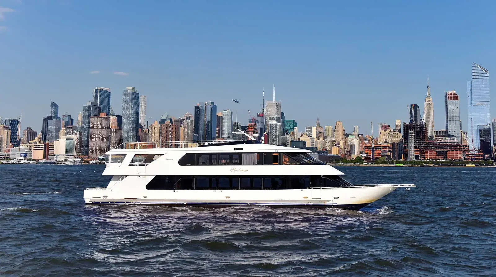Cruise ship is in the Hudson River with skyline behind it 