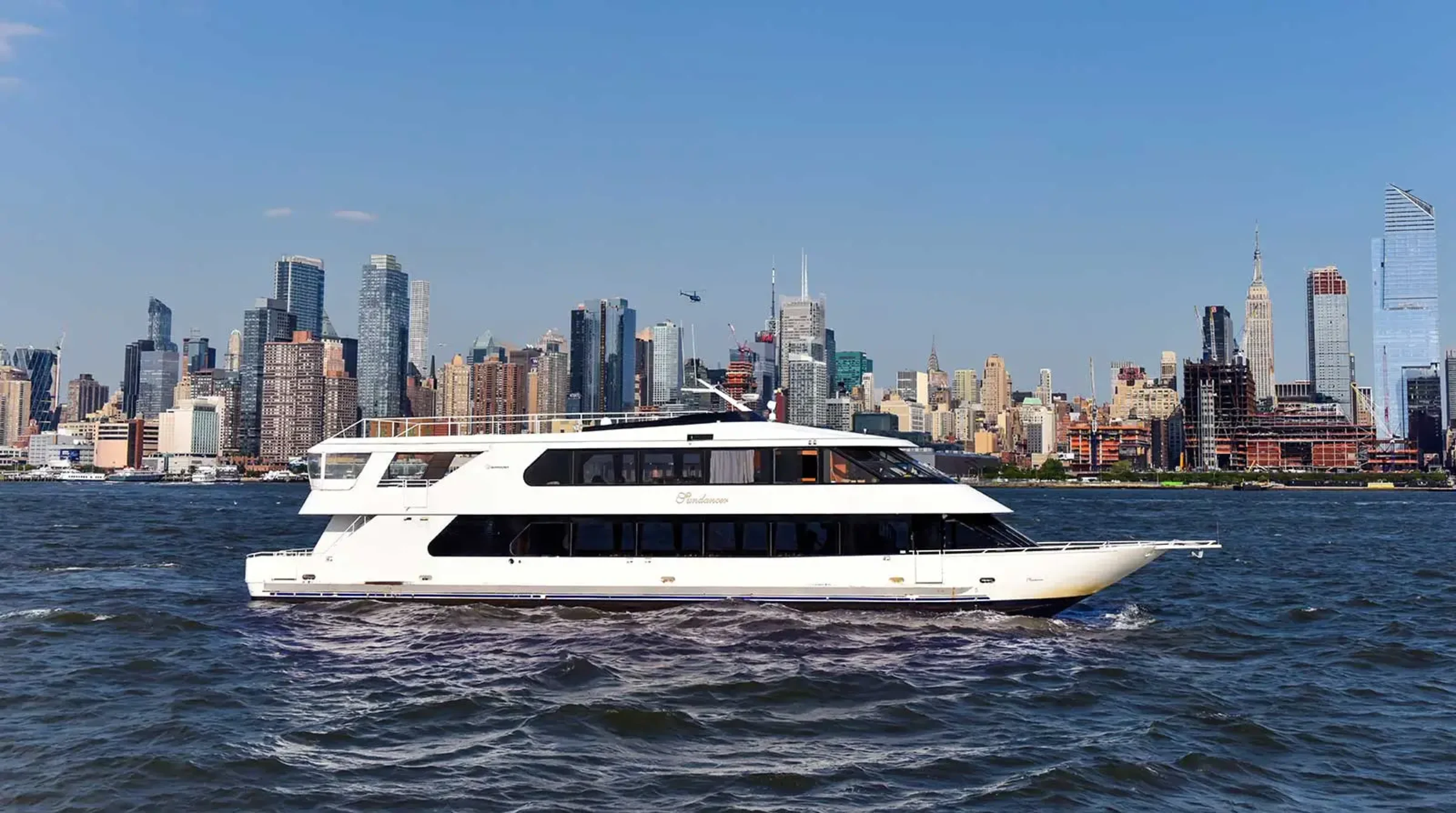 Cruise ship is in the Hudson River with skyline behind it