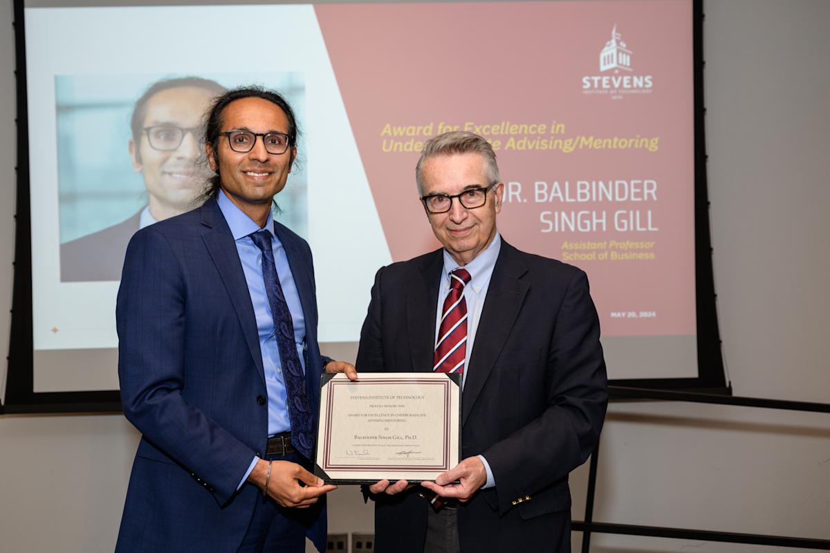 Balbinder Singh-Gill and Gregory Prastacos stand on stage holding the award certificate.