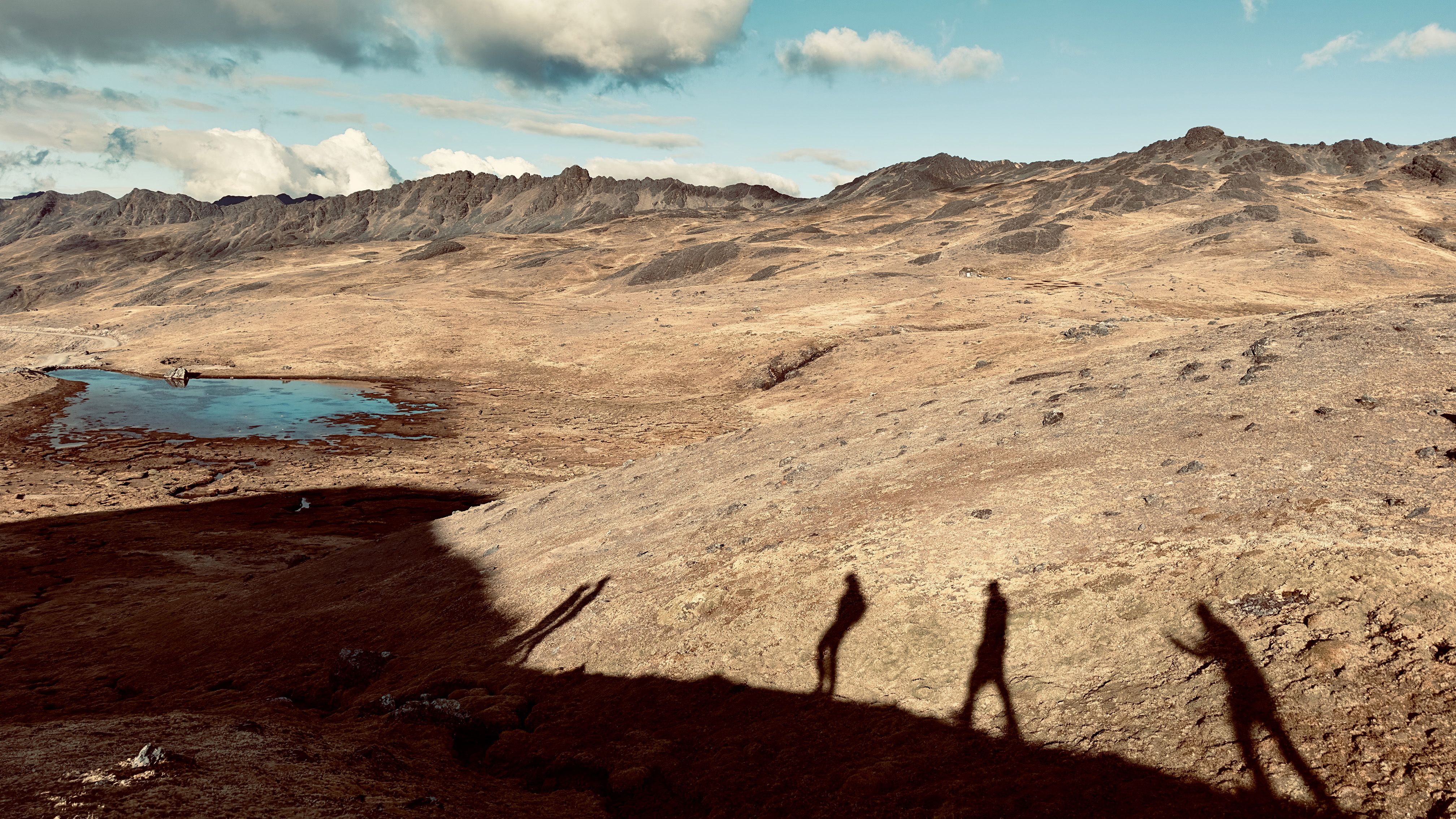 Arid landscape with shadows of people walking.