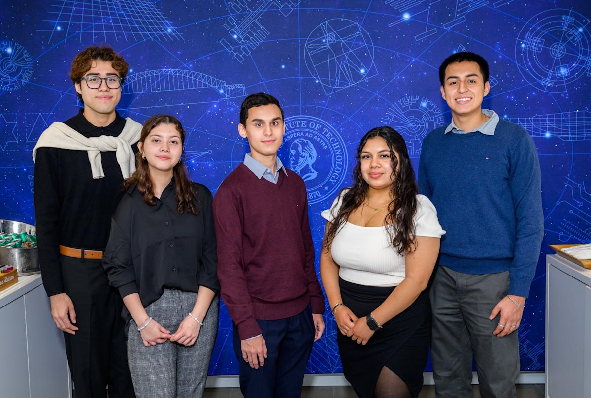 First-year students Jonathon Salmeron, Melissa Santiago, Andy Abreu, Allison Mendoza and Diego Veletanga pose in front of a blue wall. 