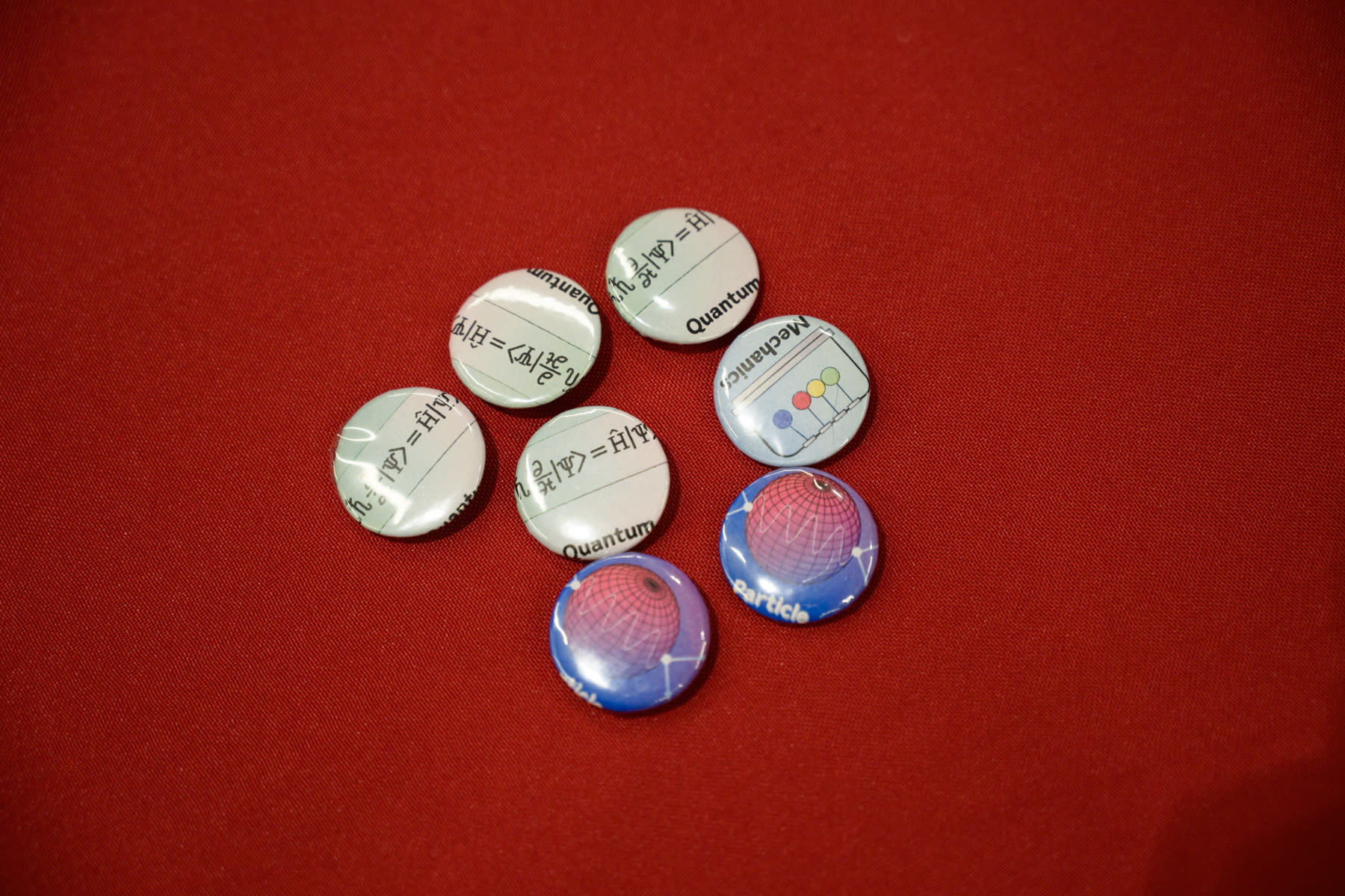  A set of custom buttons designed for the 2025 CUWIP at Stevens on a red table.