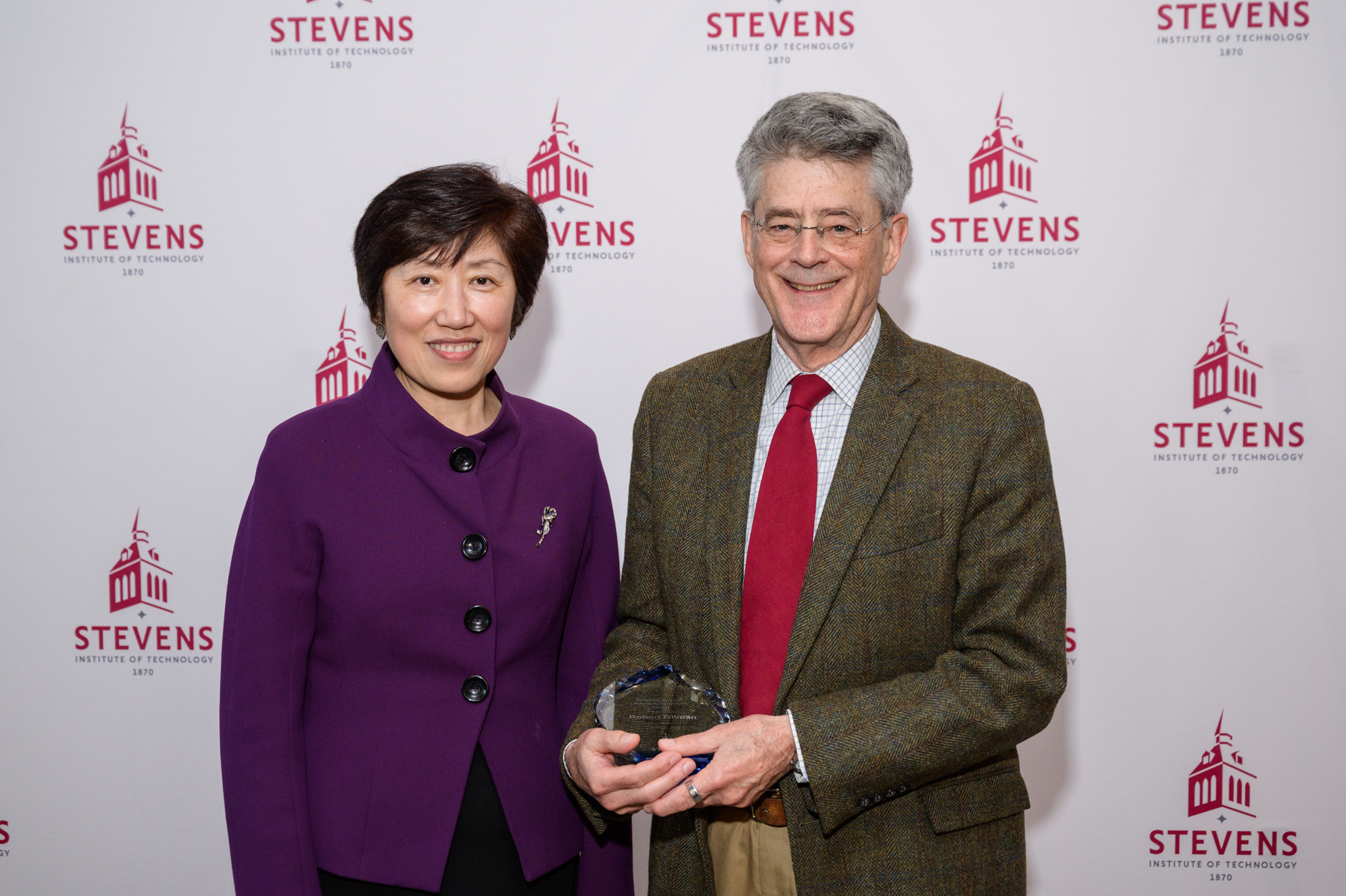 Jean Zu and Bob Gilman standing in front of a Stevens-branded backdrop