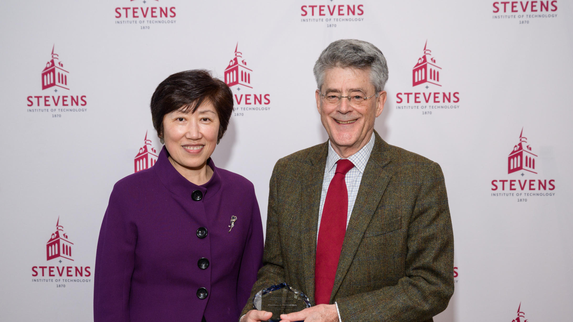 Jean Zu and Bob Gilman standing in front of a Stevens-branded backdrop