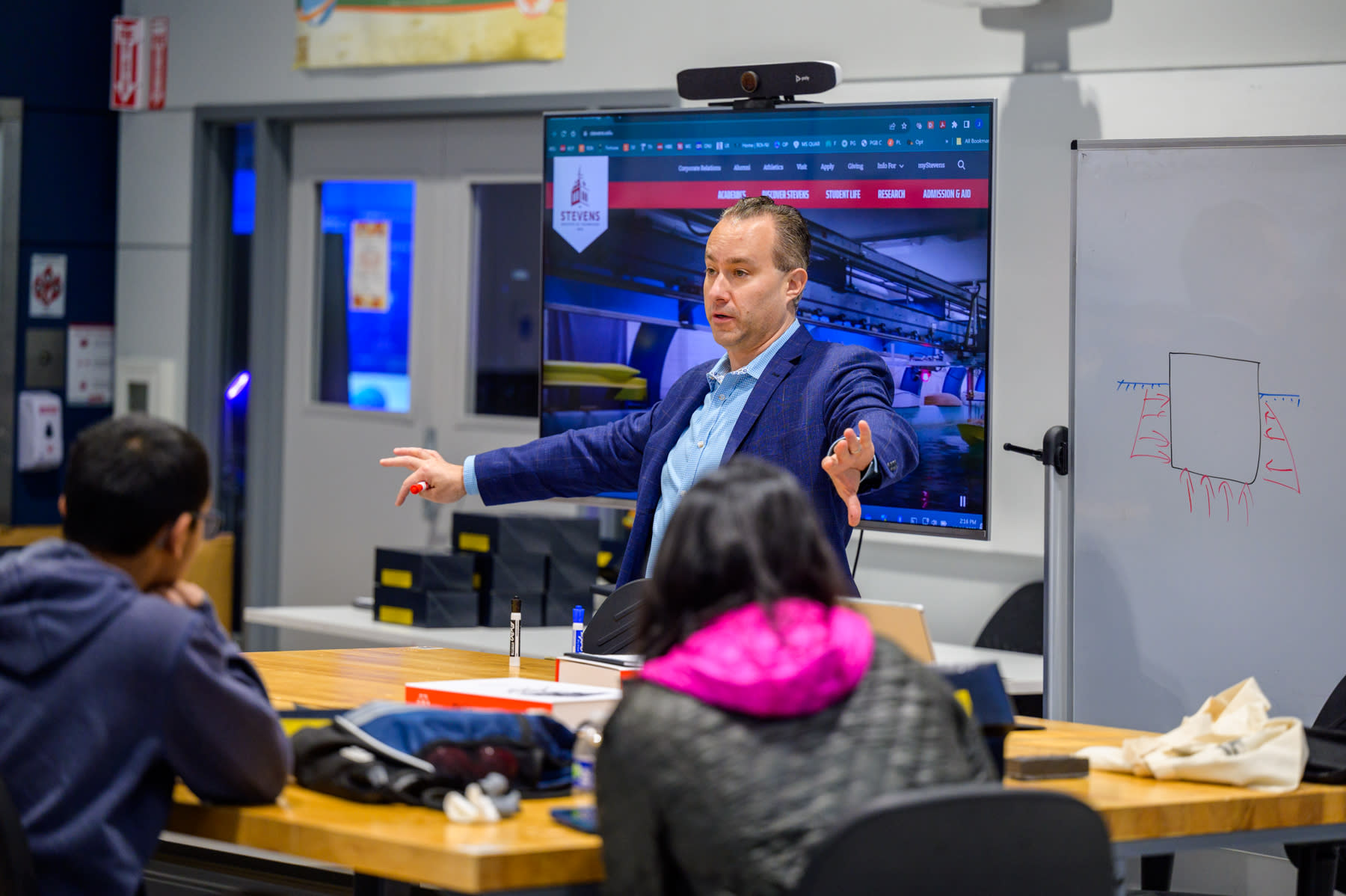 Photo of Stevens Trustee Joe DiPompeo spreading out his arms while talking to a group of students looking on