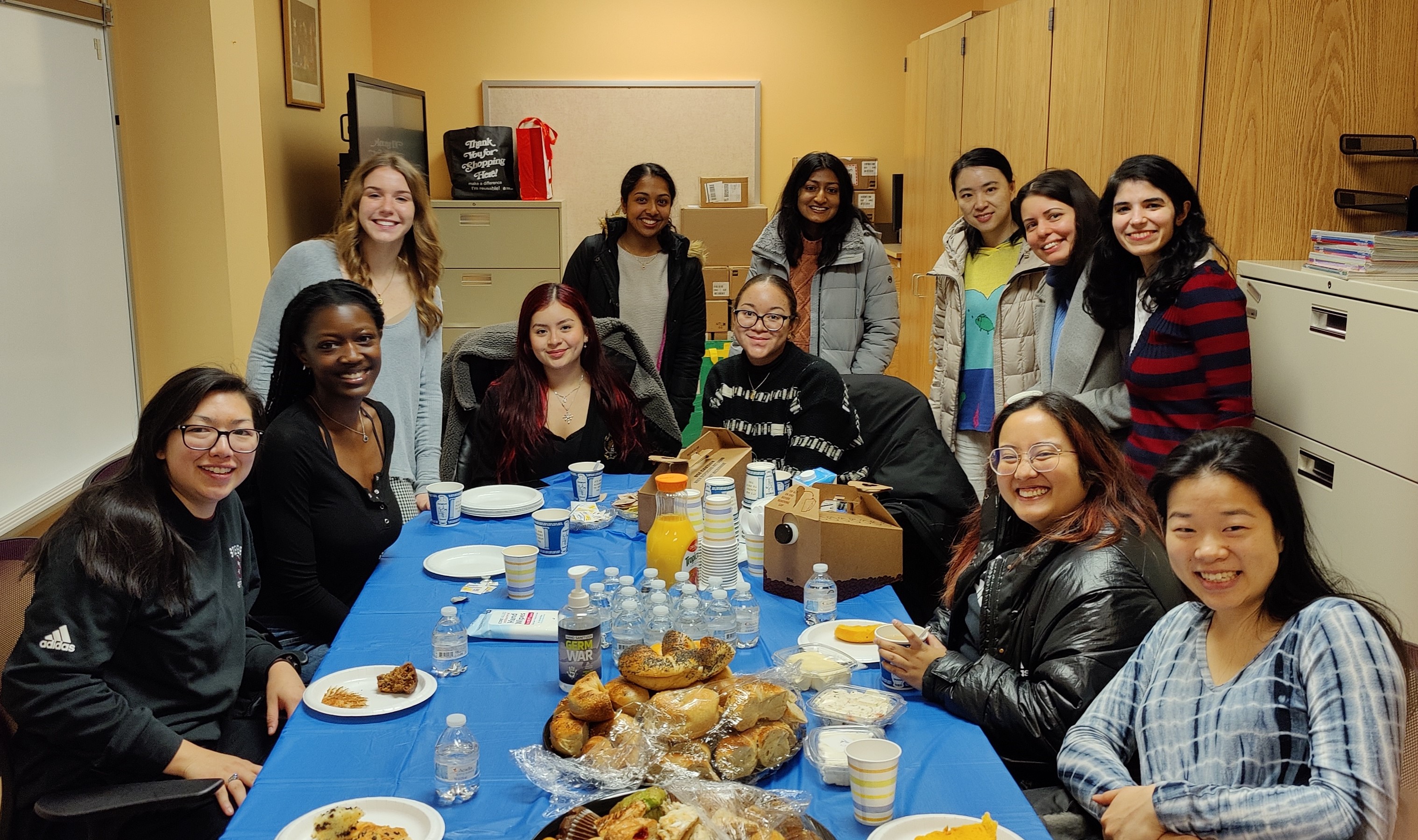 The Stevens team -- staff and students -- eat bagels around a table to celebrate their success at Introduce a Girl to Engineering! Day