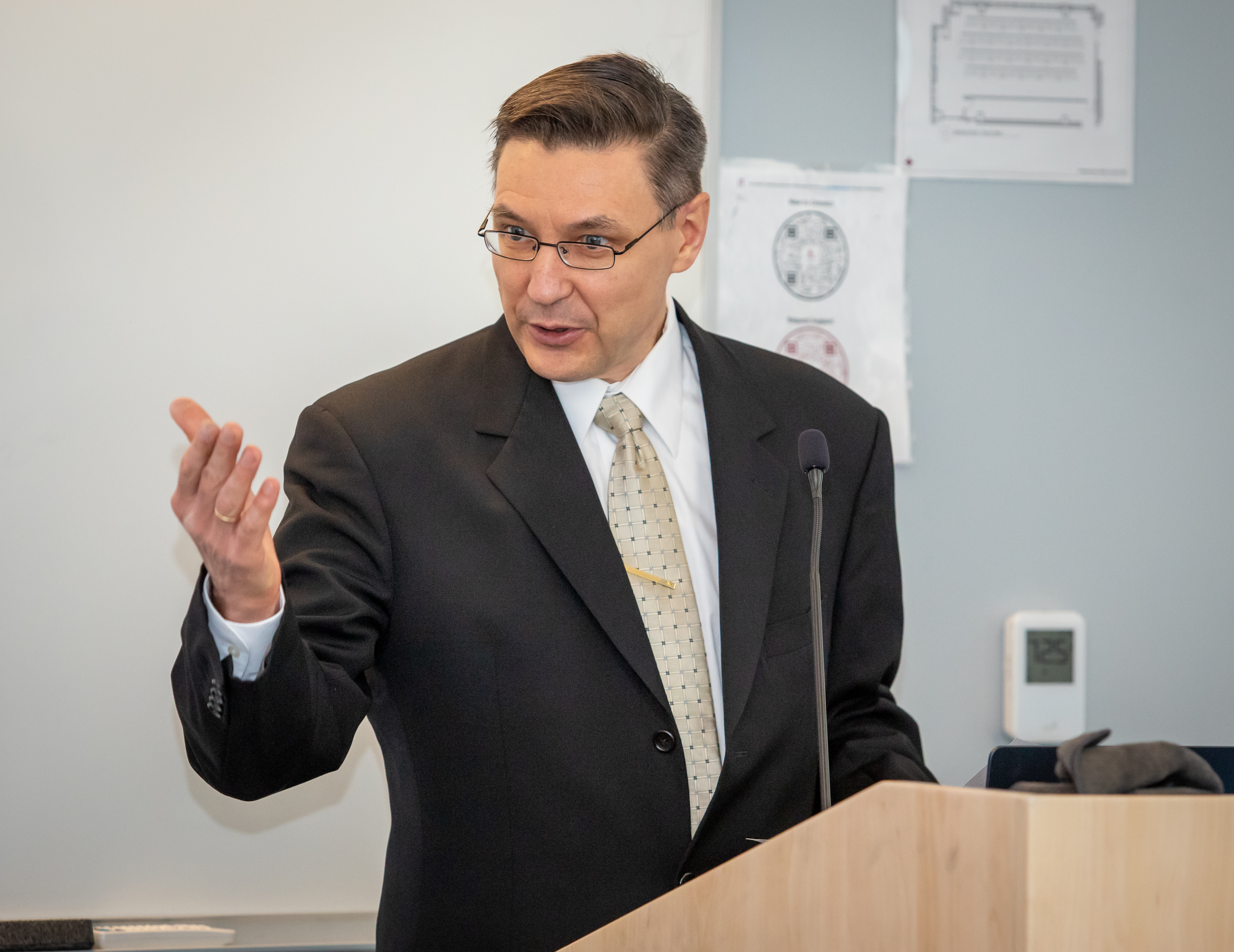 Professor Michael Zabarankin at a podium in a classroom lecturing with his right hand up