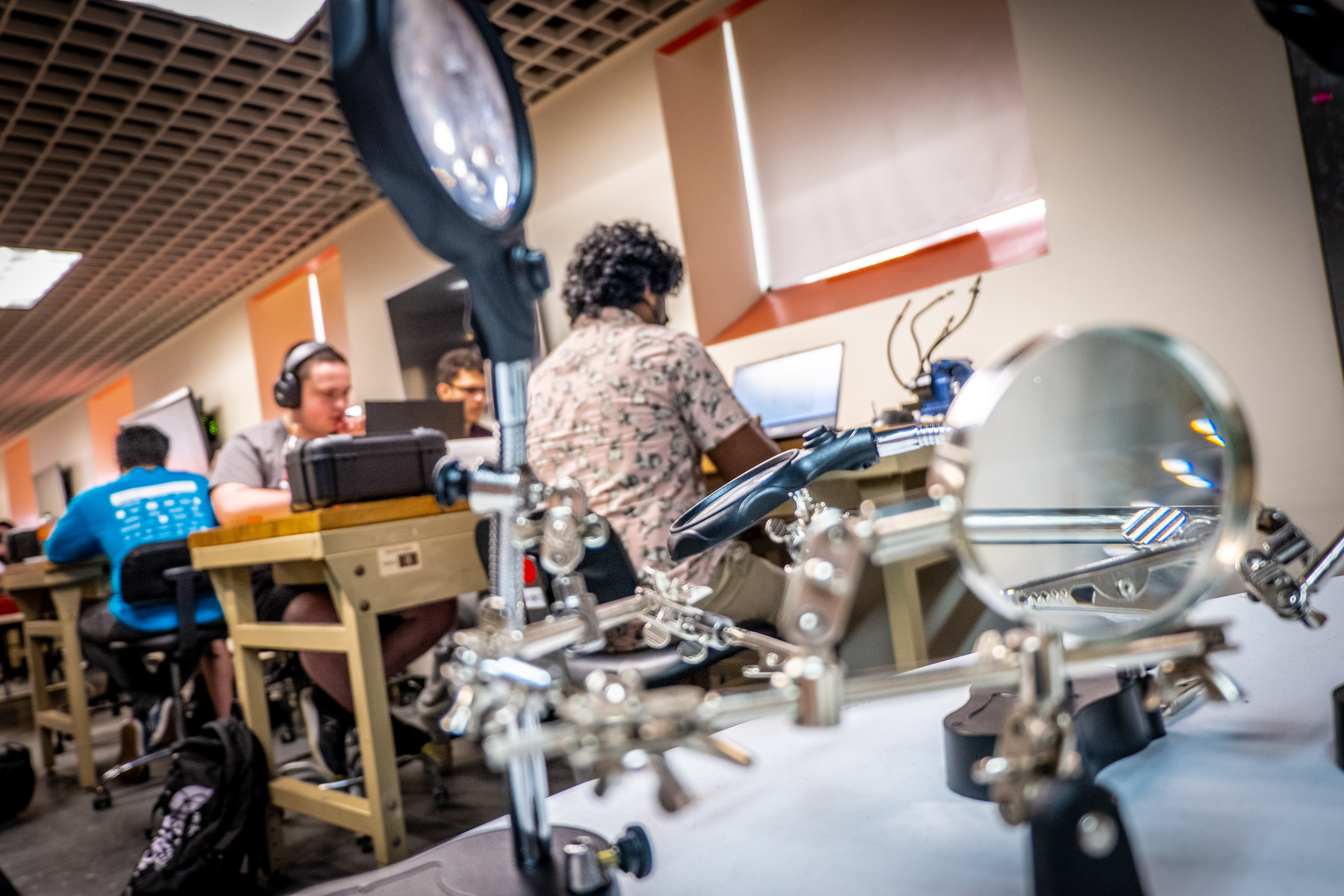 Students working at stations behind two magnifying instruments in the foreground.
