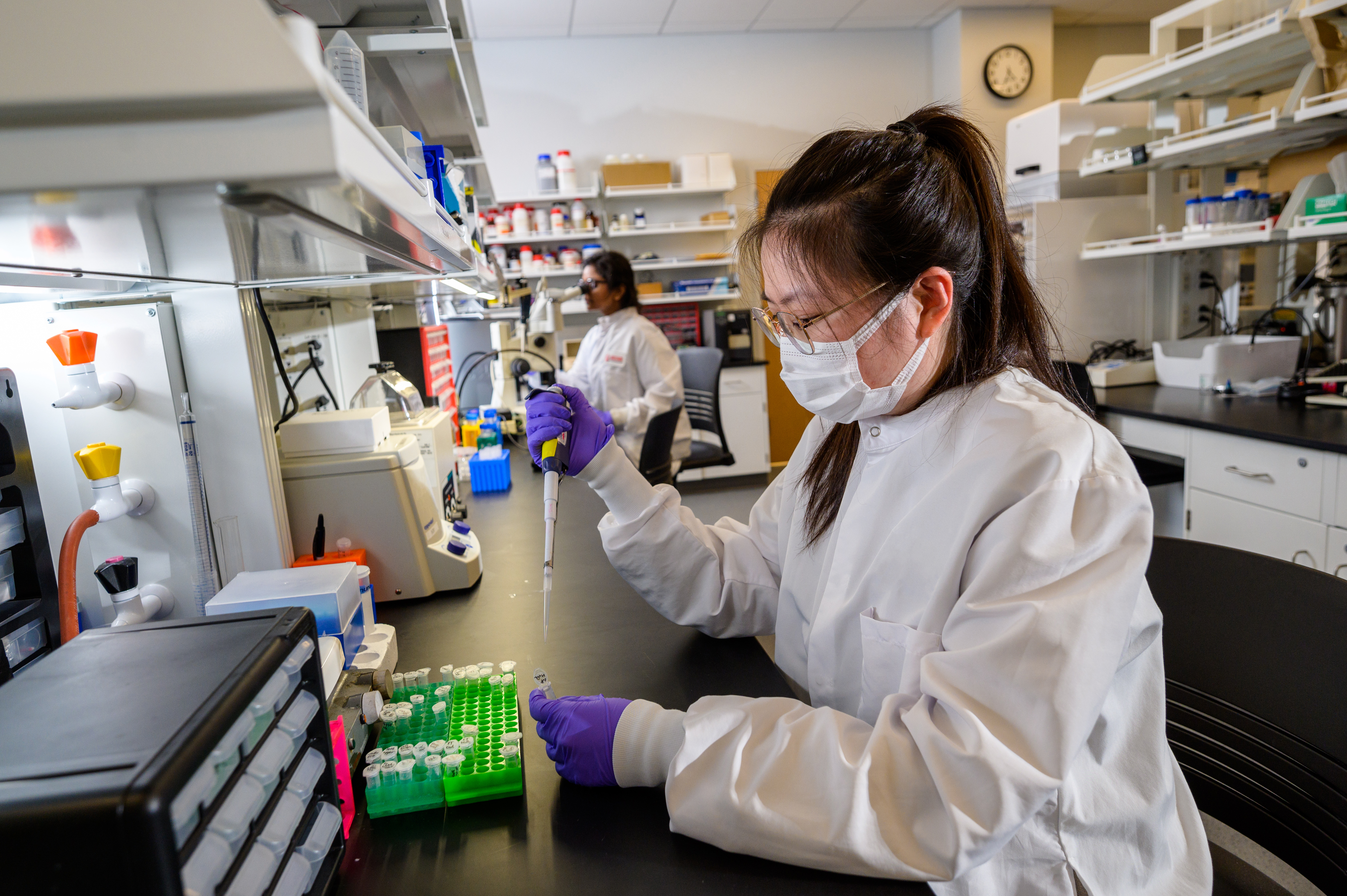 Industry Torchbearers in Healthcare - woman does work in the lab in a coat and mask