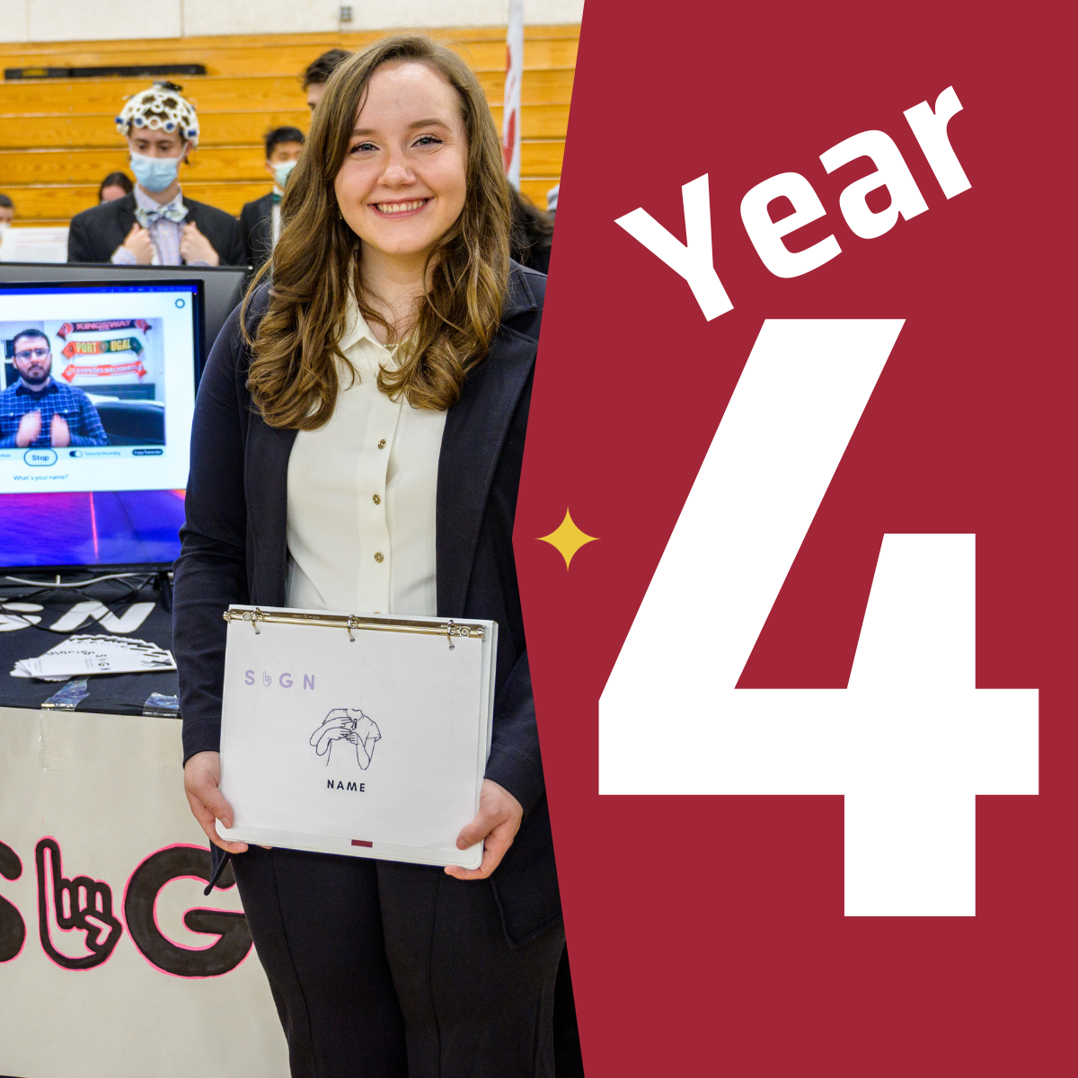 A female student standing in front of her project at innovation expo next to a graphic that says year four.