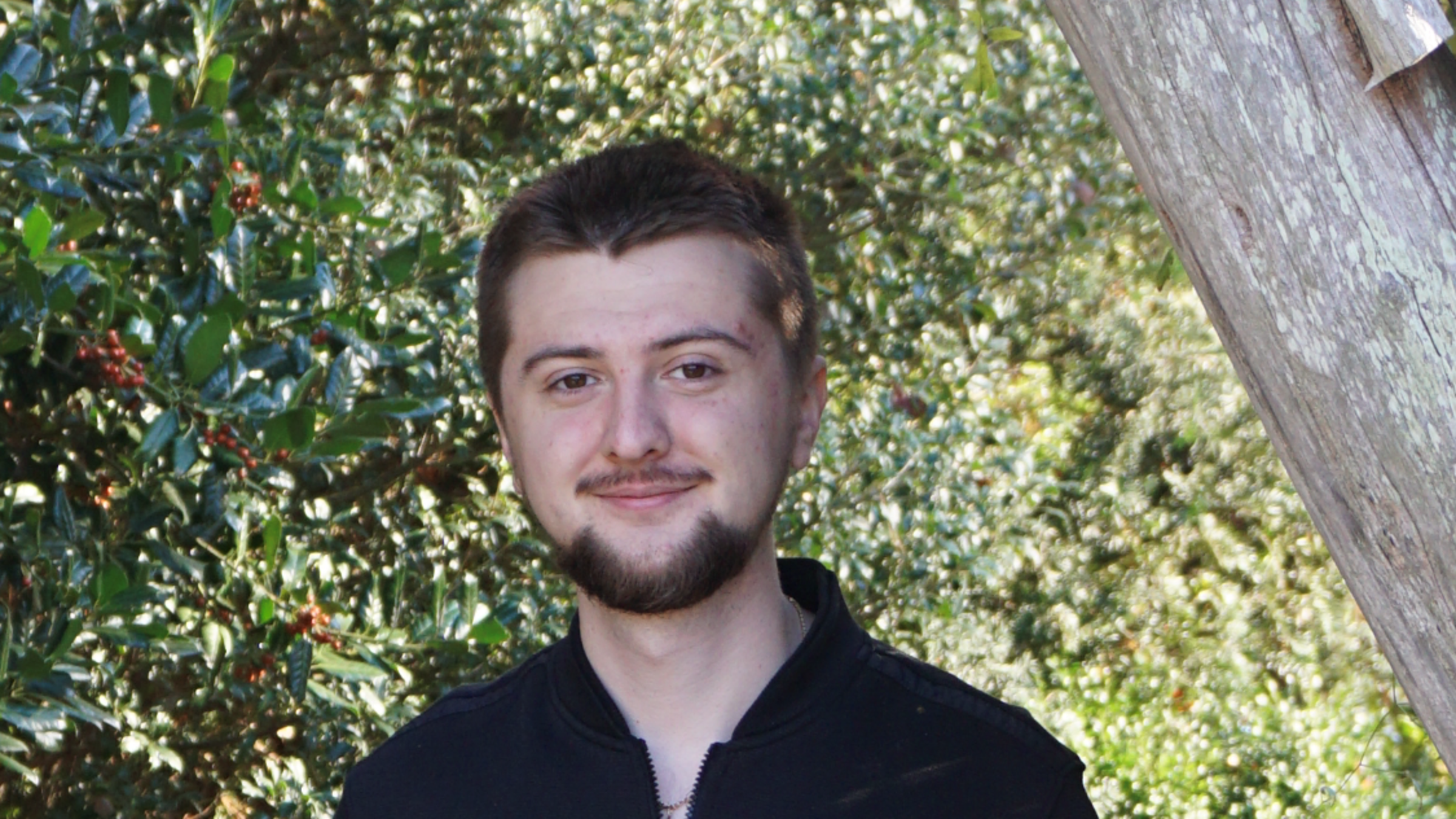 Aleksandr Grin outdoors standing near a tree