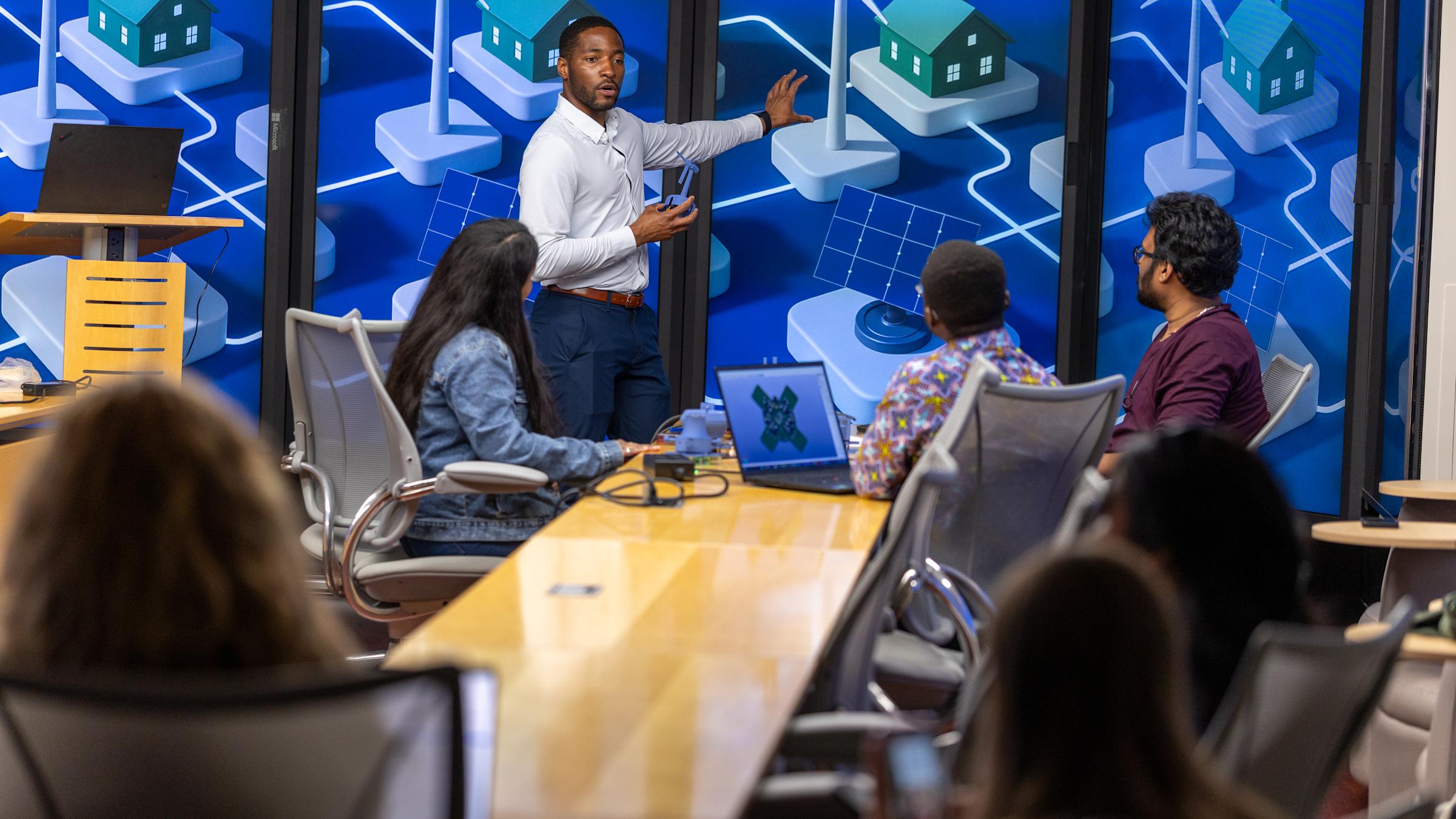 Stevens professor Philip Odonkor working with students in front of display monitors showing a city system.