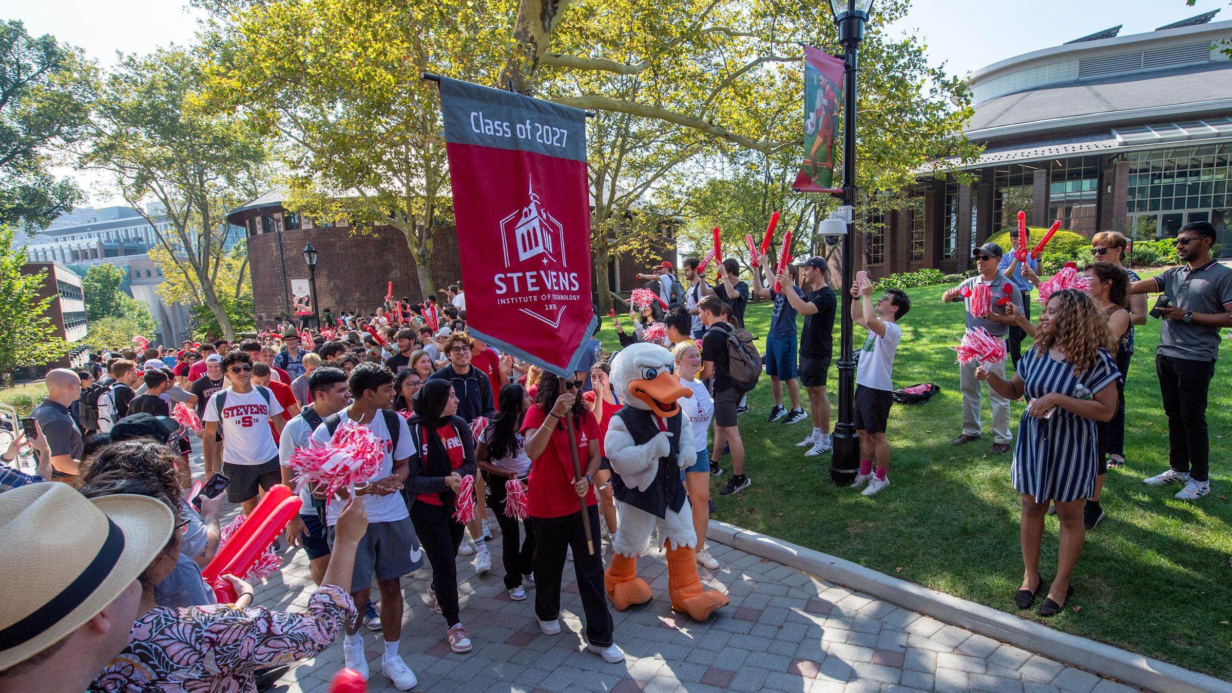 A group of students and Attila walking with a banner down Wittpenn Walk.