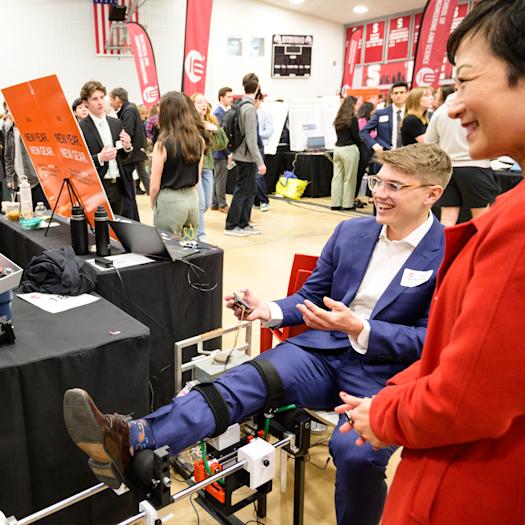A student displays the Knee-sy Does it device as three people observe a demonstration.