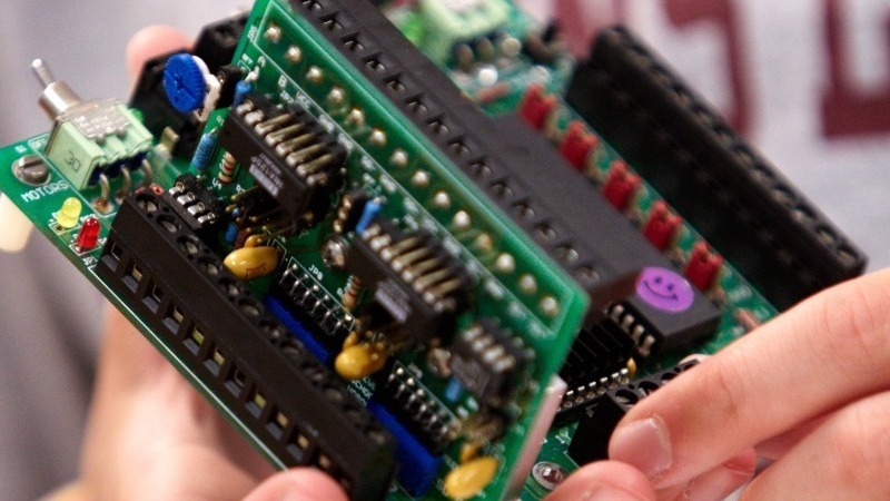 A pair of hands holding a custom-made electrical computer board.
