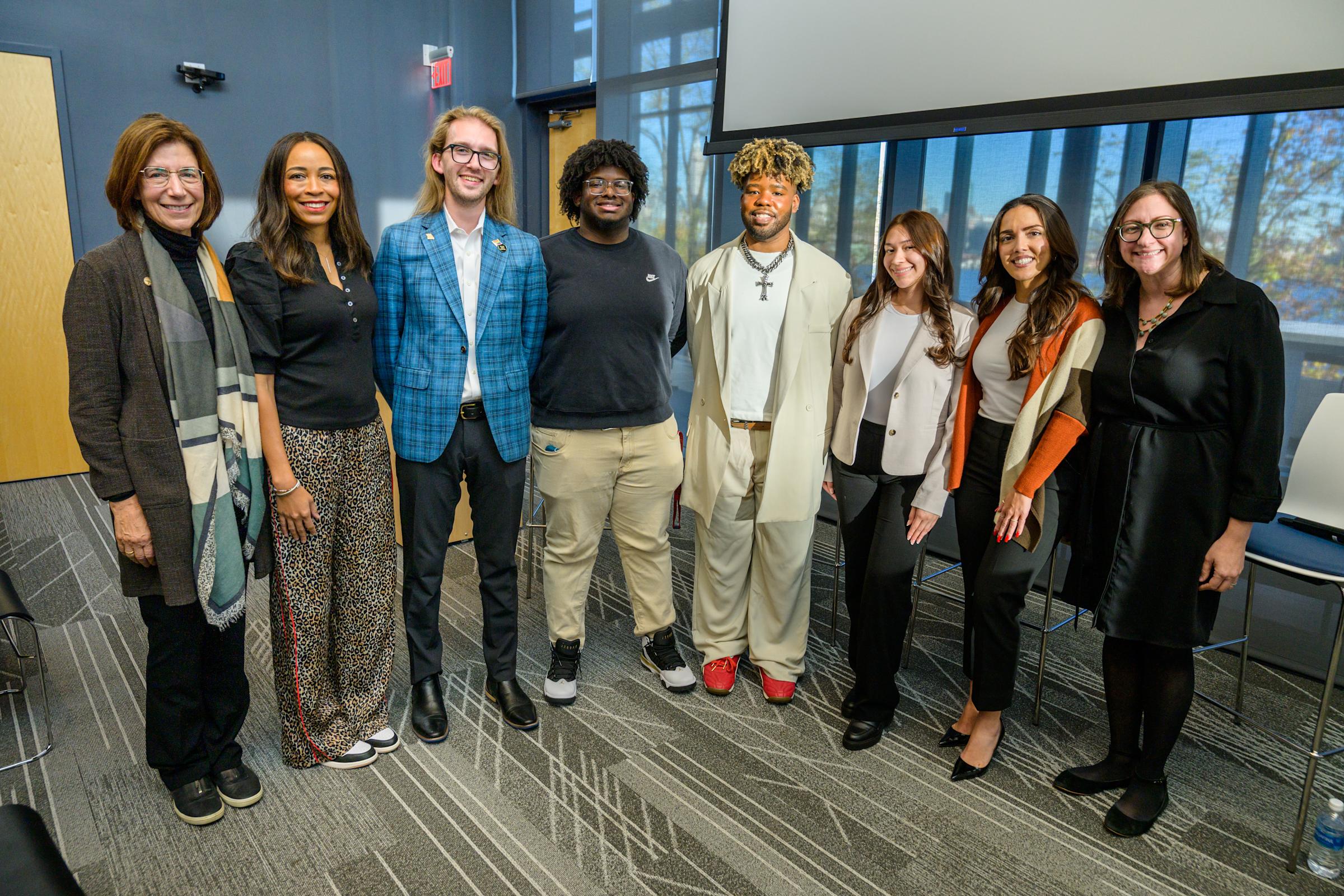 Seven people standing in front of window at the University Center Complex