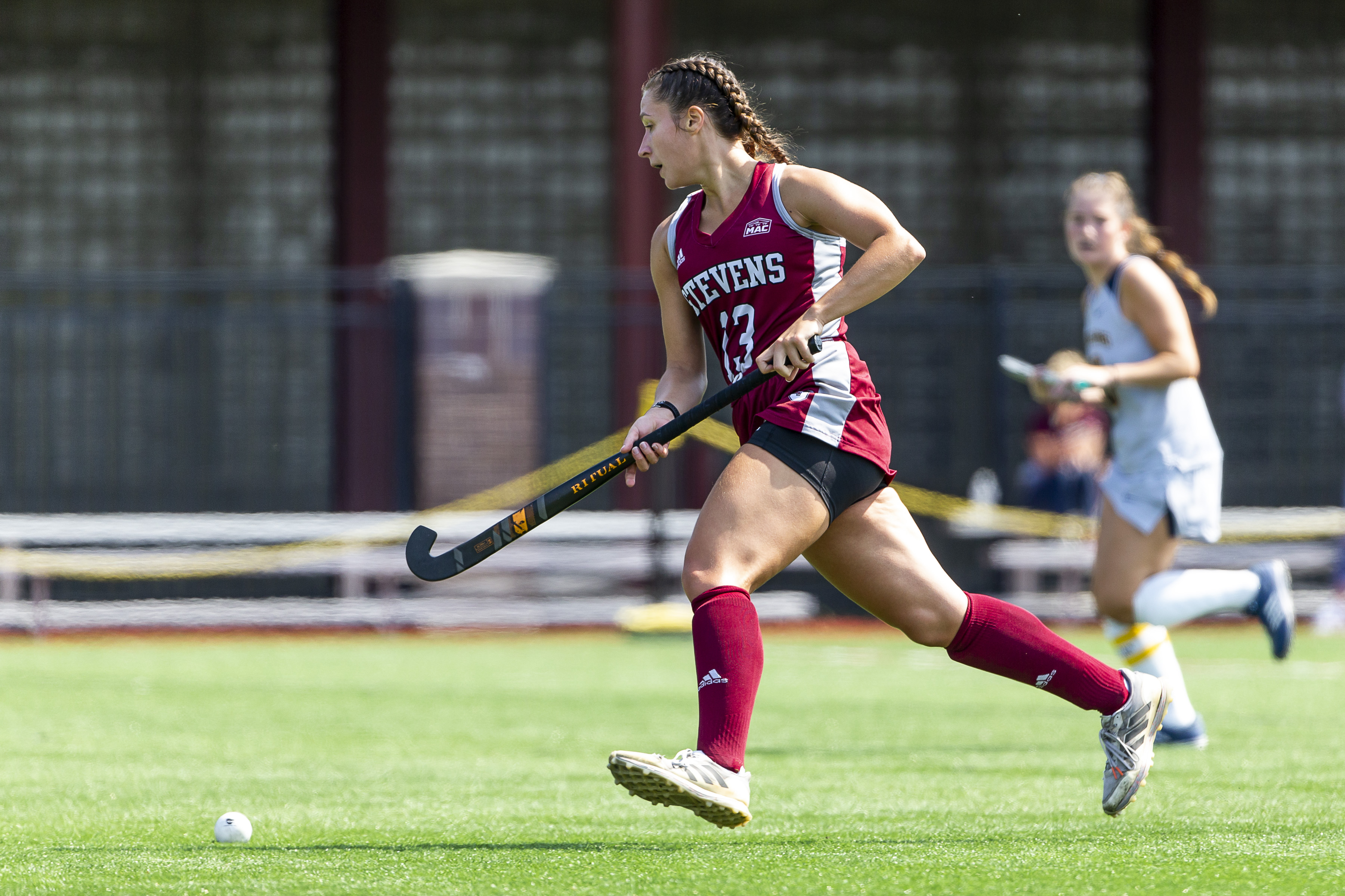 Field hockey player runs up the field with the ball